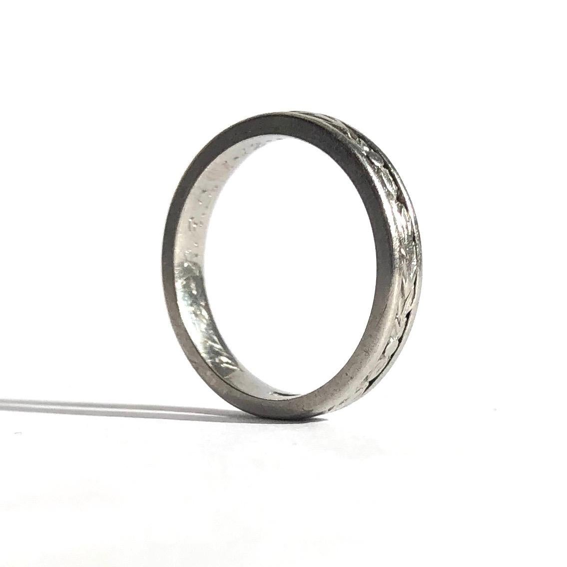 This decorative platinum band holds deep moulded leaf style detail that is framed by a solid line each side all around the band. There is an inscription inside the band which reads 'D.L.C - R.E.S 1.12.52'

Ring Size: J 1/2 or 5
Band Width: