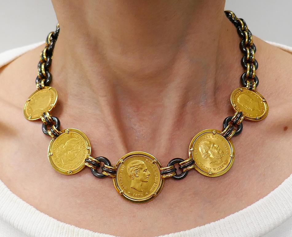 A gorgeous Faraone 18k gold coin necklace with gunmetal links. 
The necklace comprises oval gold and gunmetal loops gathered in groups of three. These loops are attached to the coins and connect gunmetal rings. A color of the dark brown metal with a