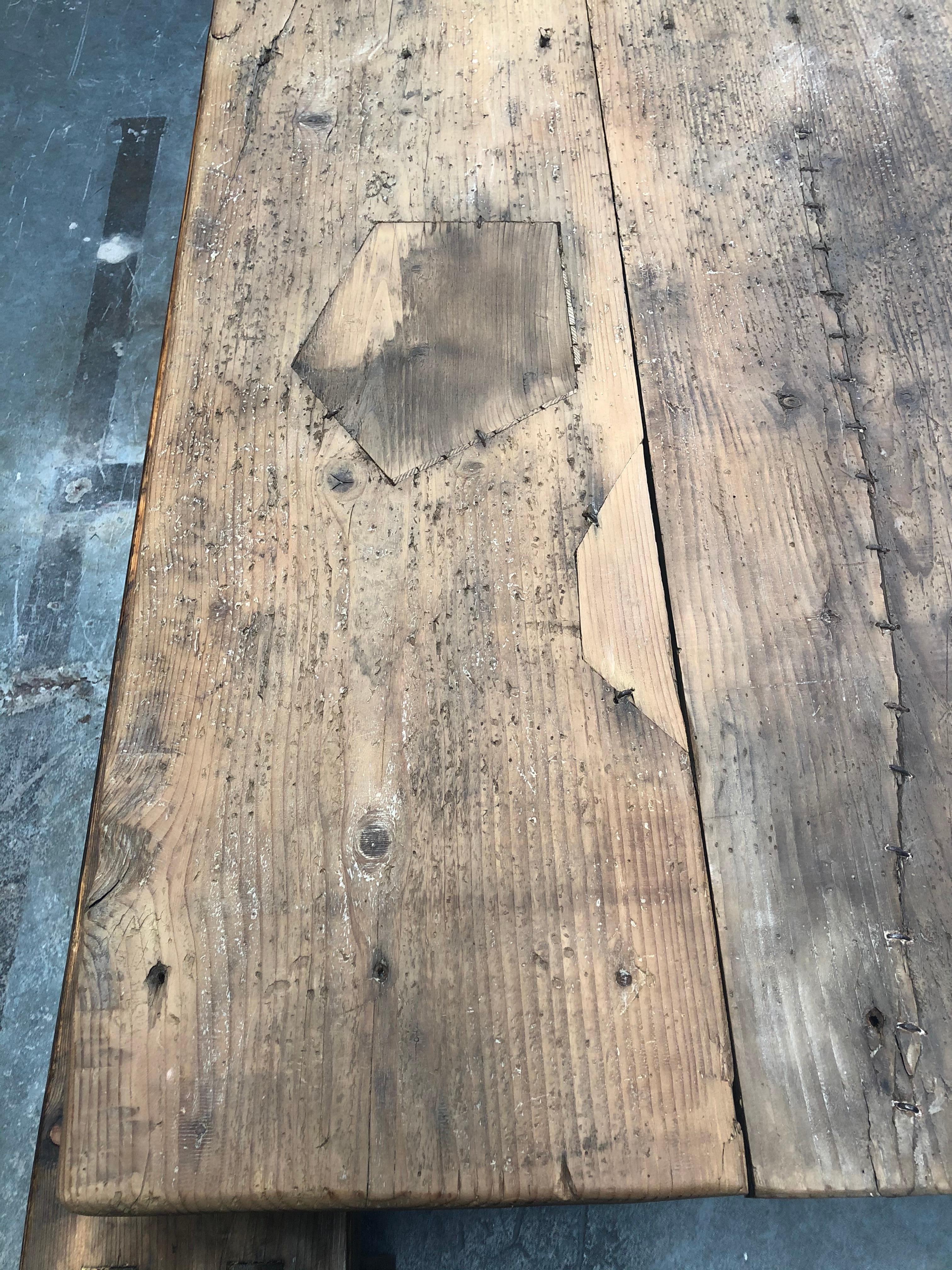 Large vintage farm house table beautifully matched with black iron legs. Farm house table is reminiscent of a Classic butcher block table. Detailed with exposed metal stitched wooden patch work. Rustic but refined. Perfect as an indoor or outdoor
