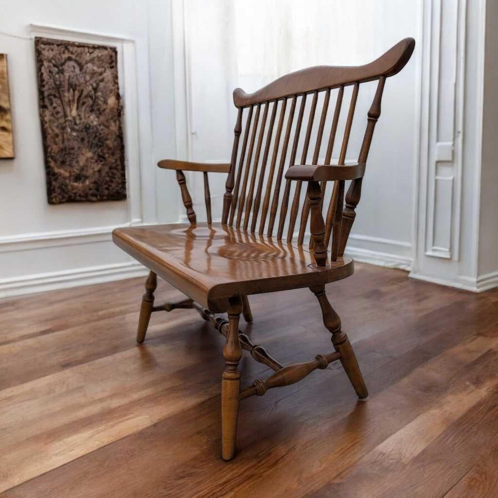A distinctive wooden bench in the vintage farmhouse tradition, crafted from solid wood and showcasing a spindle back, turned legs, and gently curved arms. This piece blends timeless Americana design with quality craftsmanship—ideal for a hallway,