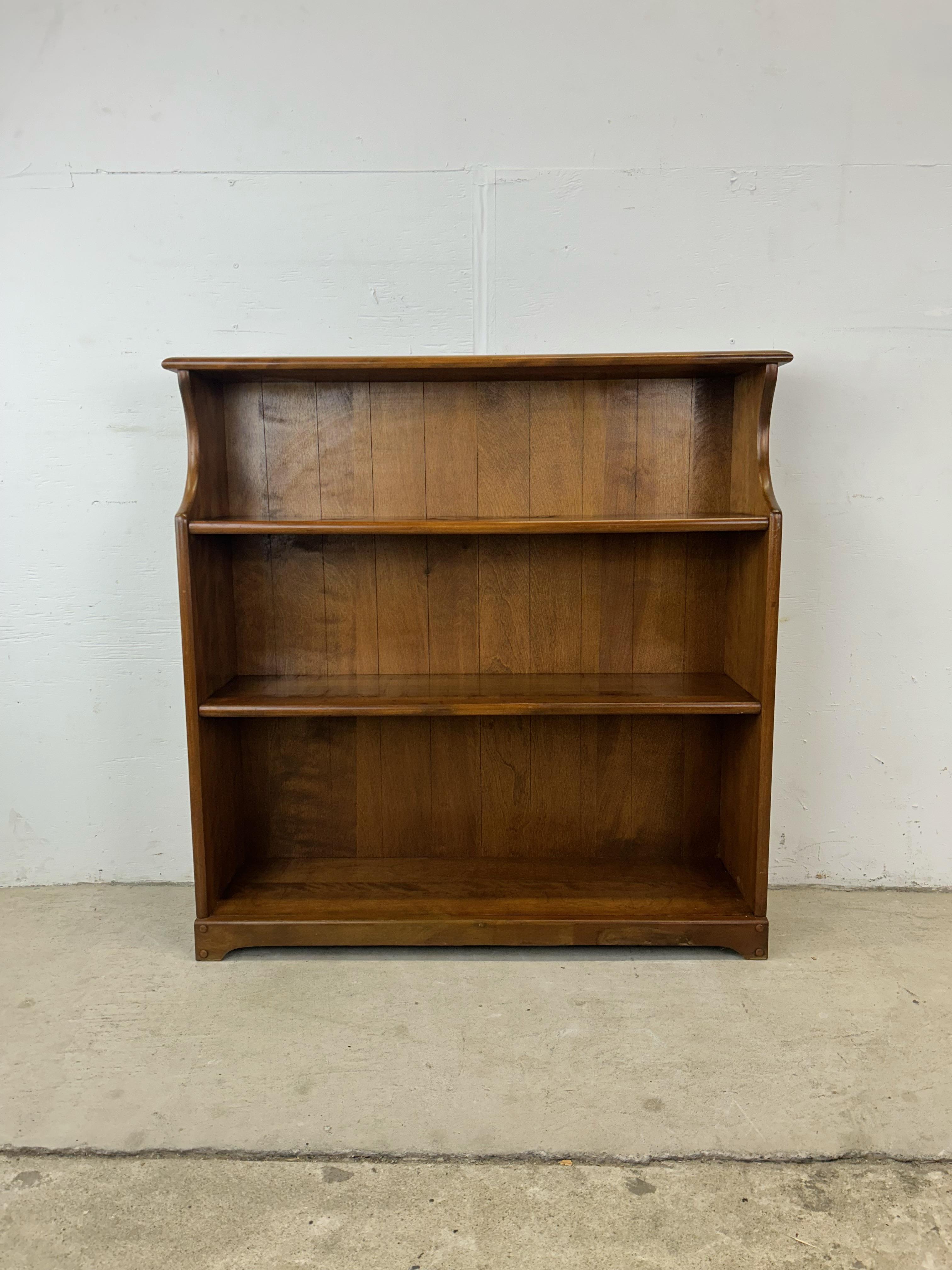 This vintage farmhouse style bookcase features solid maple construction with original finish, three shelves with open storage, and sculpted base with peg accents.  Similar taller farmhouse style bookcase available separately.

Dimensions: 36w 10d