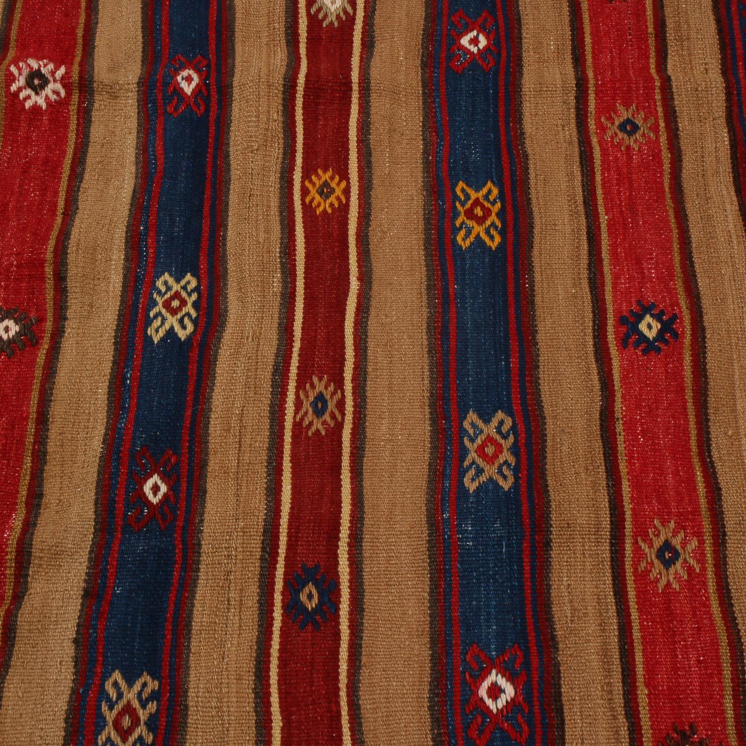 Flat-woven in high-quality wool originating from Turkey between 1930-1940, this vintage Fathiye Kilim rug enjoys exceptional condition and an inviting balance of warmth and richness in its beige-brown, multi-tonal tangerine and russet red, and navy