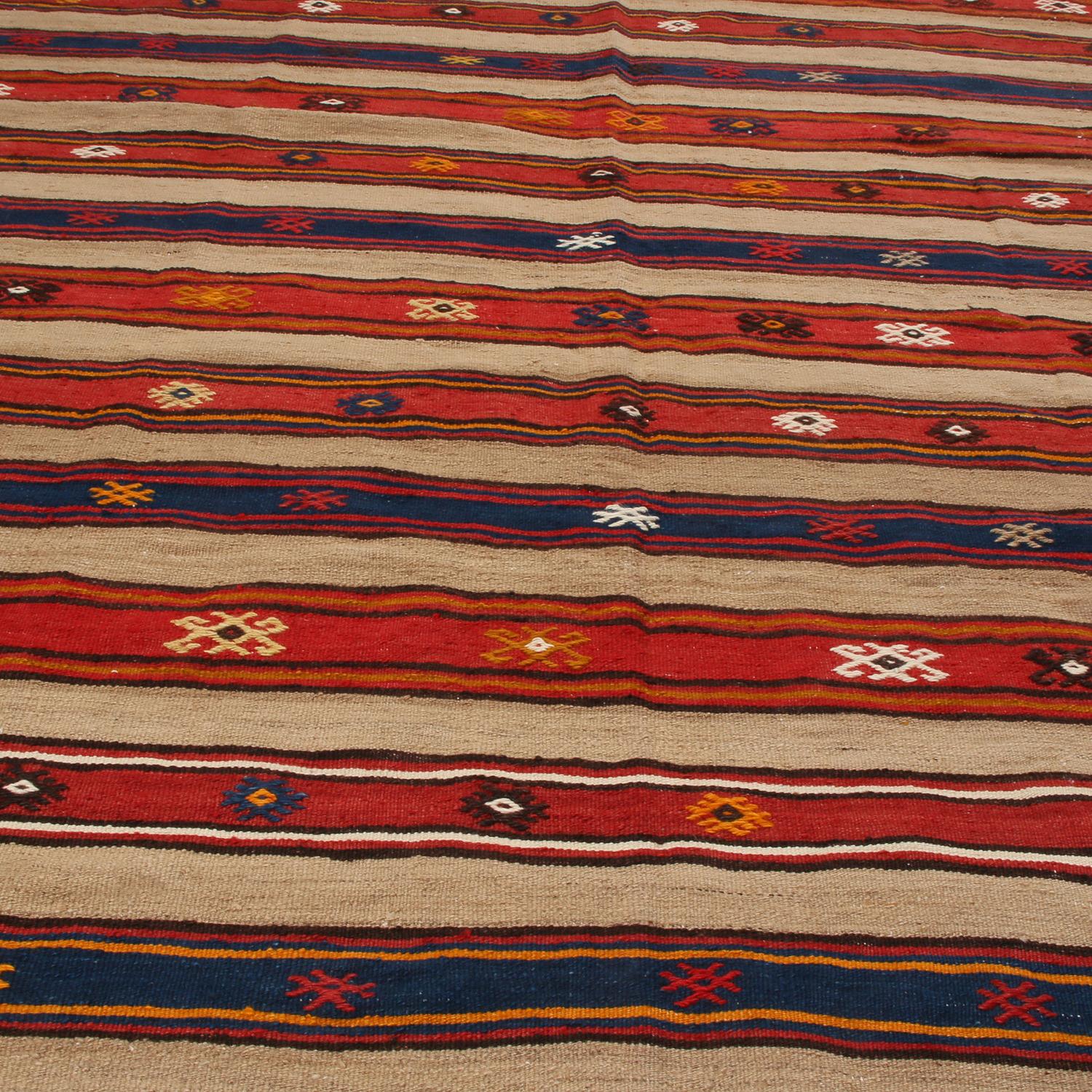 Flat-woven in high-quality wool originating from Turkey between 1930-1940, this vintage Fathiye Kilim rug enjoys exceptional condition and an inviting balance of warmth and richness in its beige-brown, multi-tonal tangerine and russet red, and navy