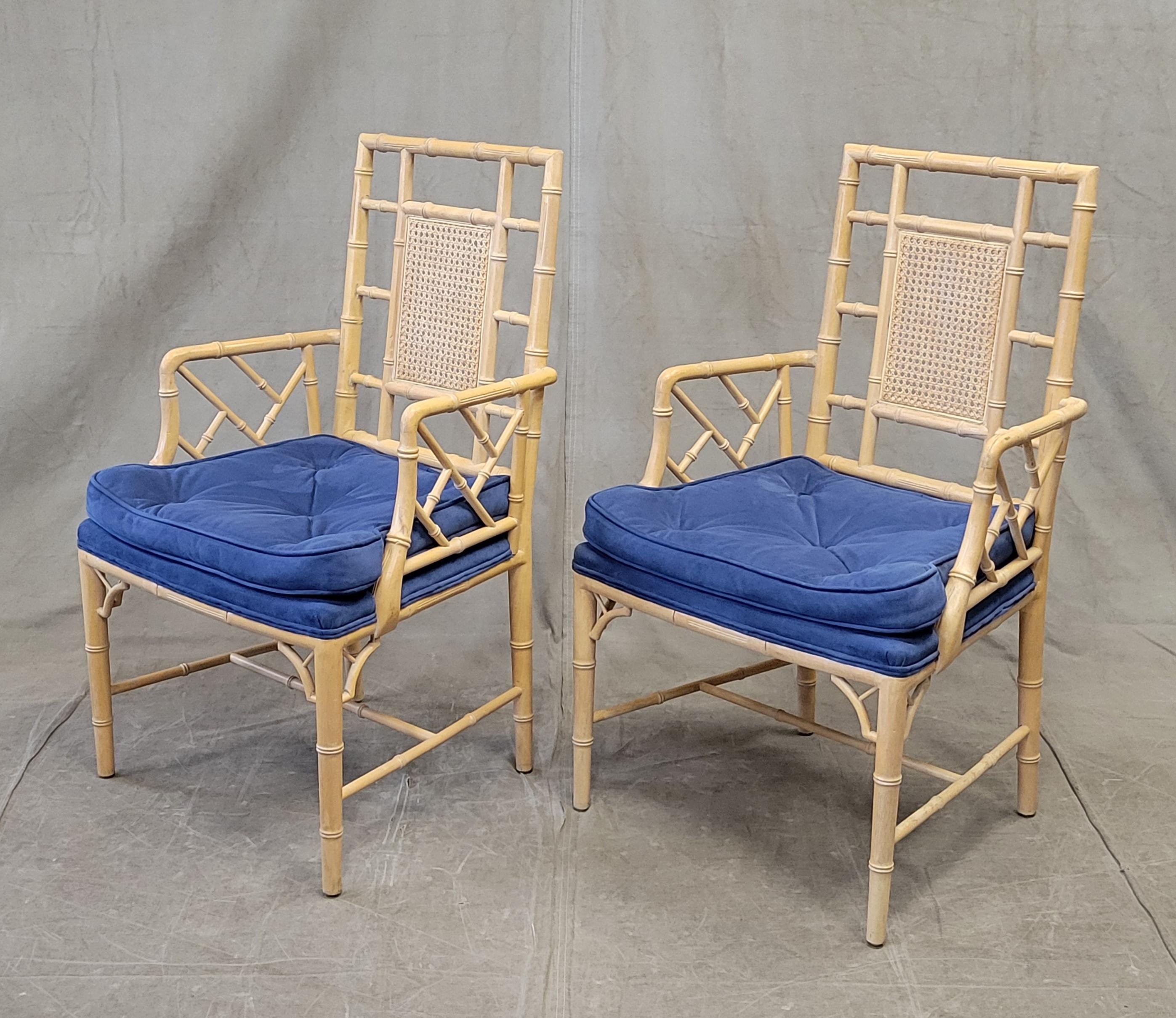 A charming and functional pair of vintage faux bamboo armchairs with tufted blue microsuede seat cushions. The wood was skillfully carved and finished to resemble bamboo and the cane back is intact and strong. Slight wear from contact with water on