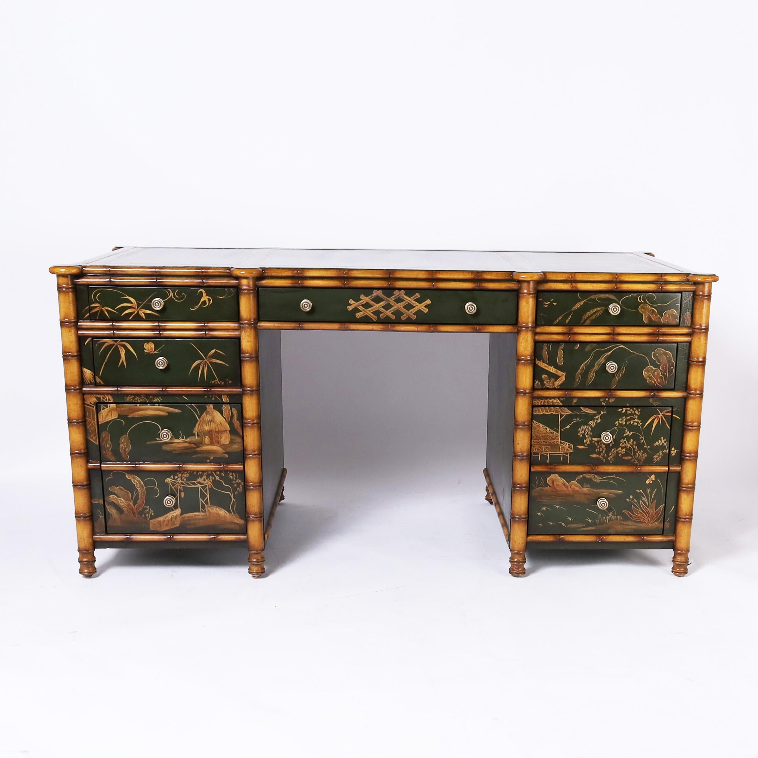 Impressive vintage desk having a tooled green leather top on a classic two pedestal form crafted with a hardwood faux bamboo frame having nine drawers in the front and two cabinets on the reverse all hand decorated with dramatic chinoiserie against