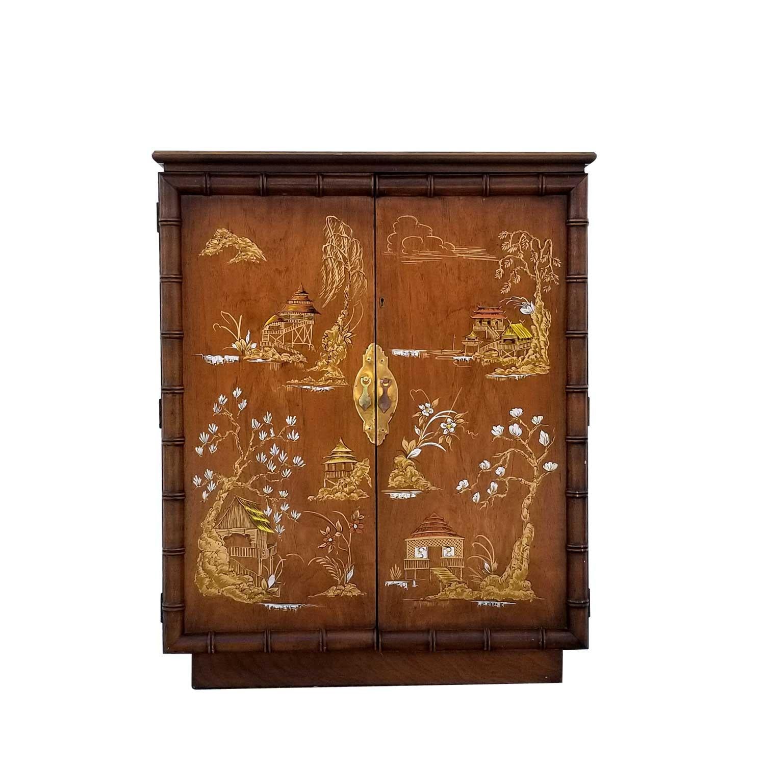 Vintage bar cabinet by Lane Furniture company. The exceedingly charming design features a hand painted Oriental edifice. The facade is further adorned with faux bamboo trim. The Chinese and bamboo elements are very on trend. Open the doors to reveal