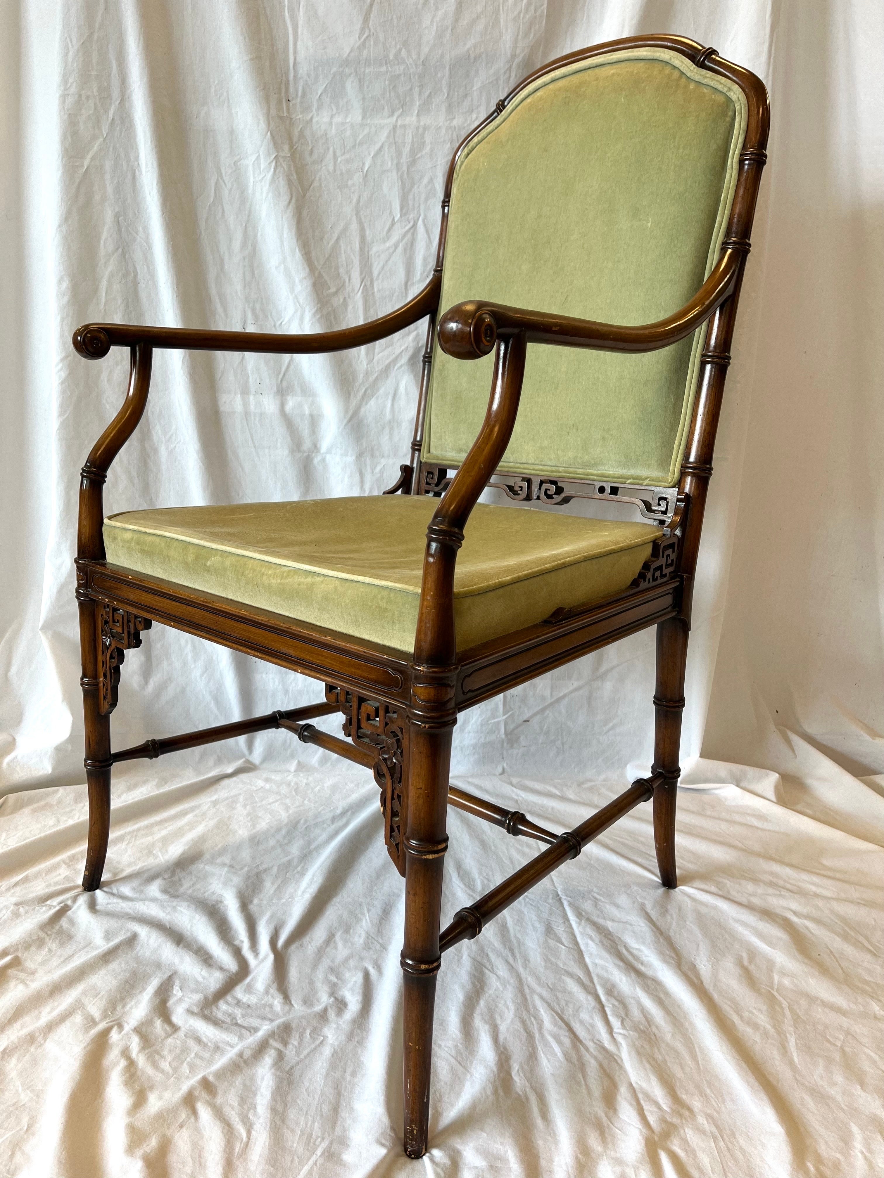A vintage, mid 20th century era Chinoiserie or Chinese Chippendale or Regency style faux bamboo and upholstered armchair with open Asian style fretwork, scrolling arm rests and domed back rest. A truly beautifully designed chair that will serve you