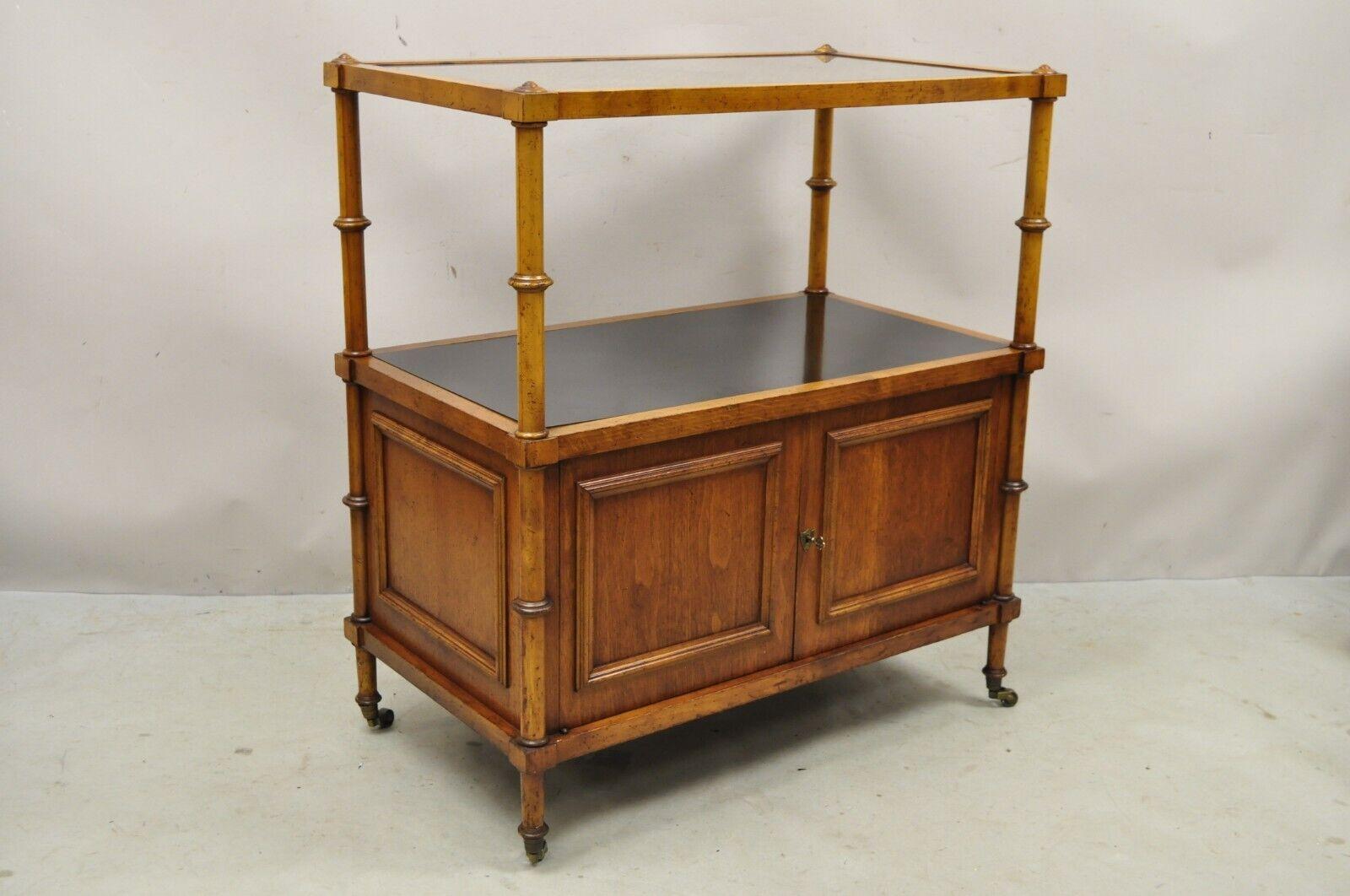 Vintage Faux Bamboo Hollywood Regency 2 Tier Cane Top Bar Cart Server Cabinet. Item features a cane top with glass surface, black laminate lower shelf, rolling casters, finished back, 2 swing doors, working lock and key, very nice vintage item.
