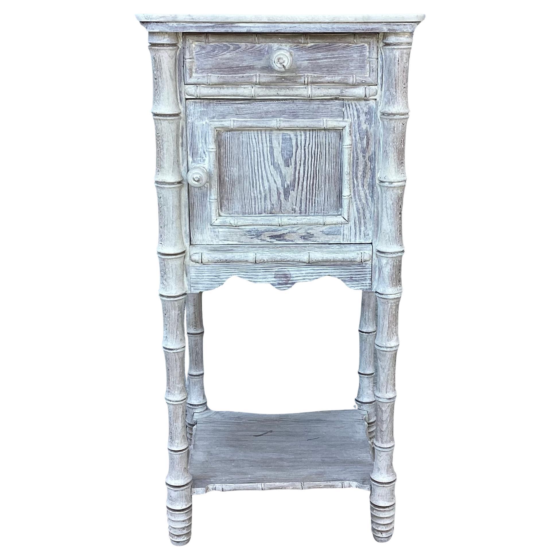 Charming vintage faux bamboo nightstand or side table with brown marble top. Table features a top drawer and a bottom shelf with door opening, and four turned post legs for support. Has a distressed finish for a well-worn patina to add to the charm. 