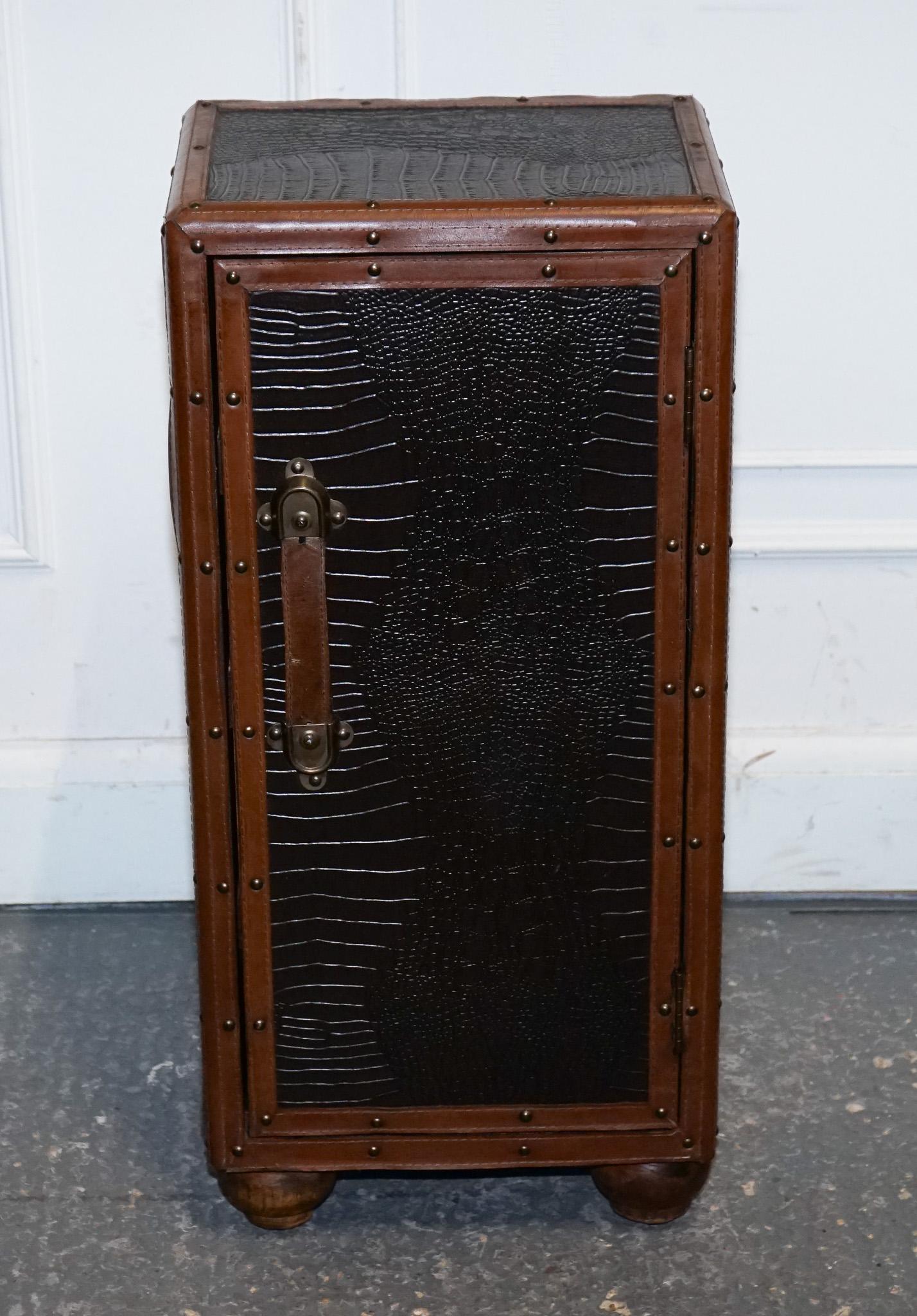 
Antiquités de Londres


Une élégante malle-armoire vintage en faux cuir de crocodile dans un riche ton brun, pleine de caractère et d'attrait décoratif. Conçue pour ressembler à une malle de voyage classique, cette pièce présente des panneaux en