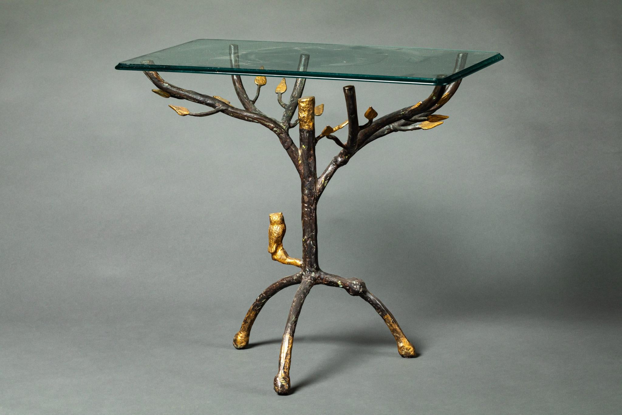 Glass top table designed with gilded leaves and a perched owl.