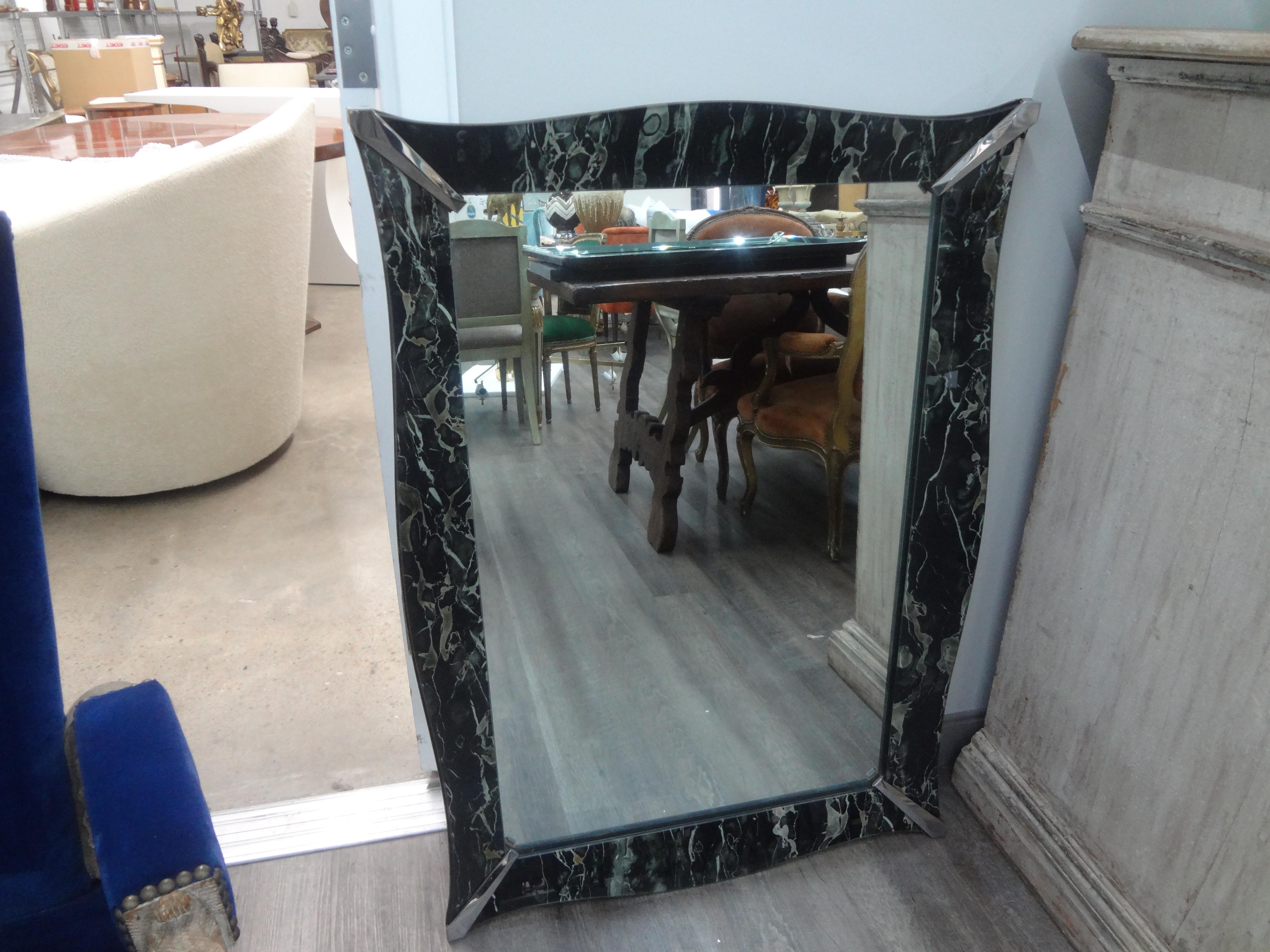 Vintage faux marble eglomise Venetian style mirror.
This unusual rectangular Venetian style mirror has a perimeter of marbleized eglomise glass with a central mirrored panel and chrome corner detail. Our lovely Hollywood Regency mirror can be