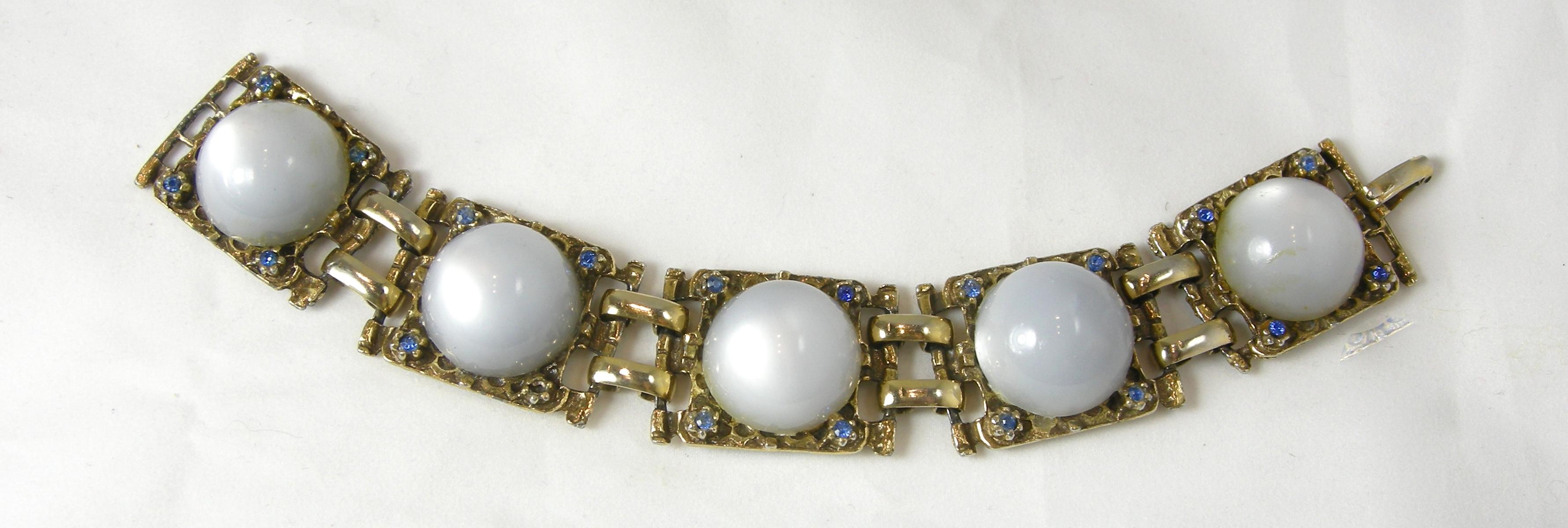 This vintage bracelet has large cabochon faux moonstones with blue crystal accents in a gold tone setting.  In excellent condition, this bracelet measures 7-1/2” x 1” with a fold-over clasp.
