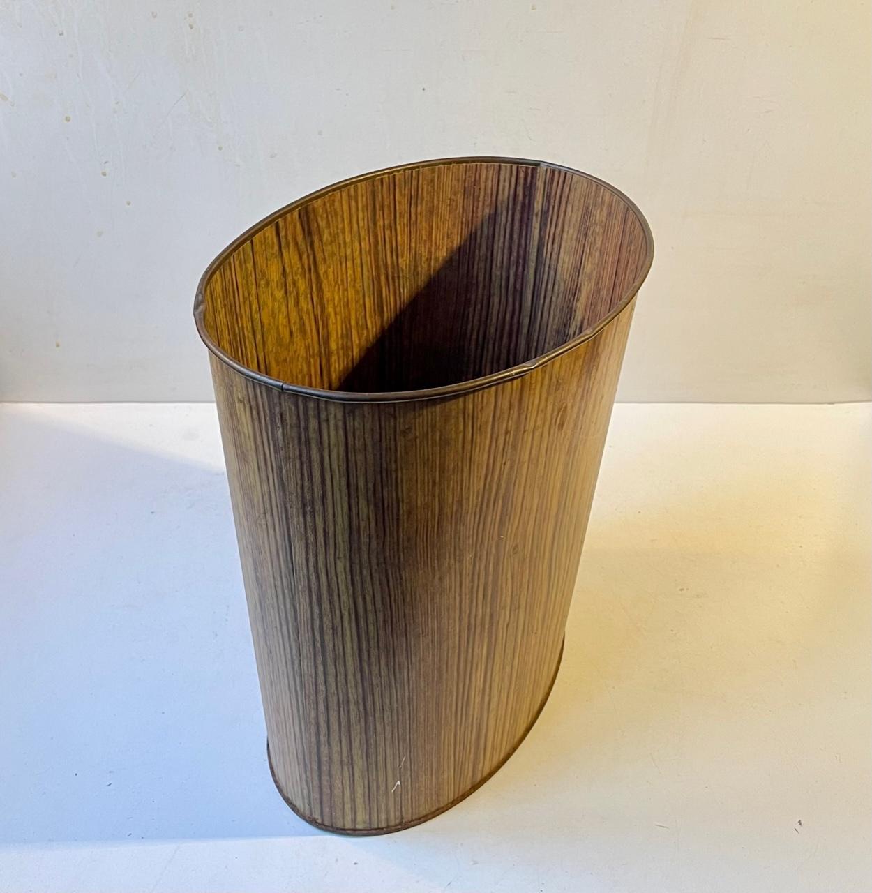 A rare oval trash can for paper/desk litter. Its made from Tin-plate covered by a faux oak foil. Made by Ira in Denmark circa 1960. Measurements: H: 28.5 cm, W: 27.5, D: 19 cm.