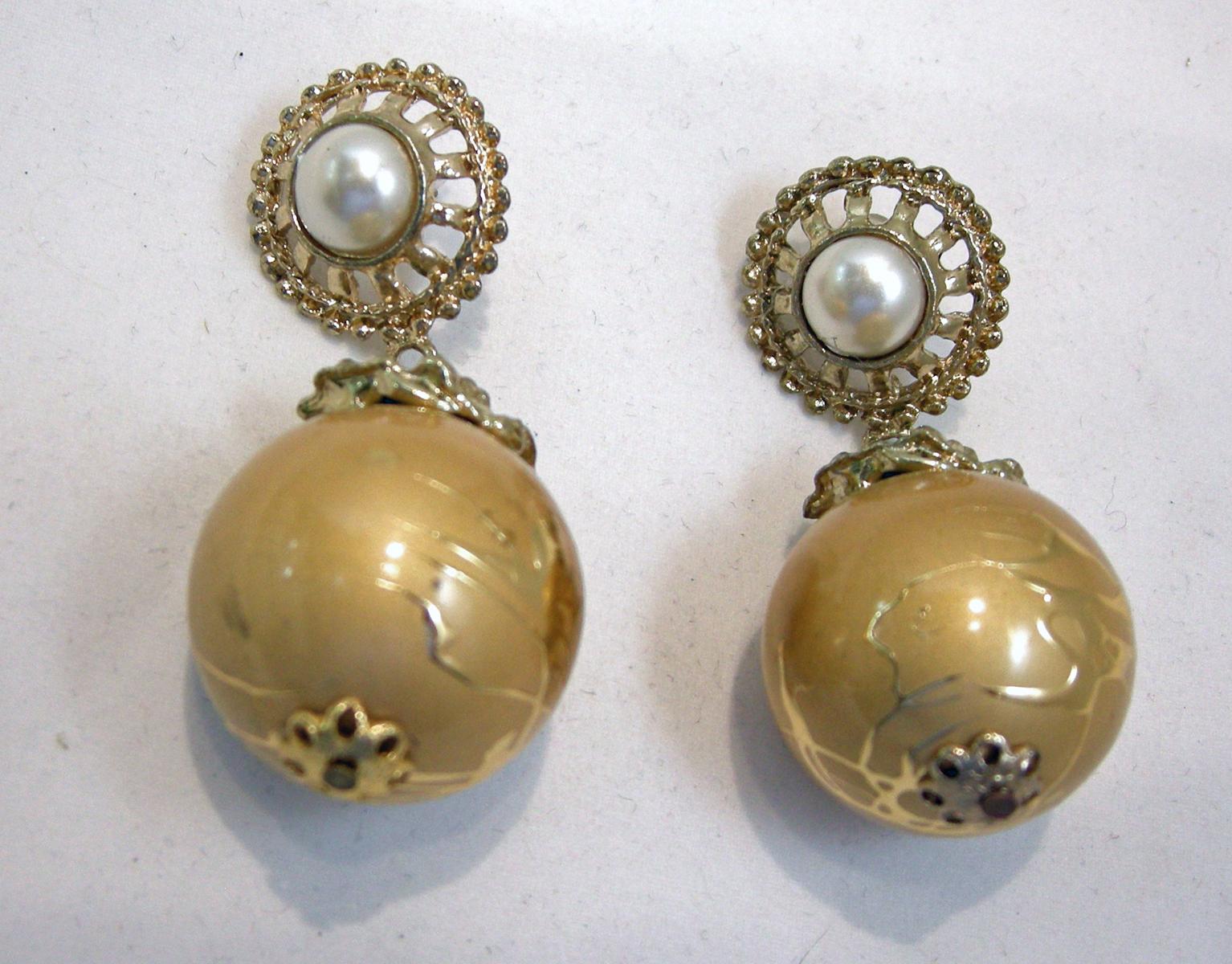 These vintage earrings have a faux pearl top encircled with rhinestones. It has a gold tone ball drop with a swirling design.  These clip earrings measure 2-1/2” x 1” and are in excellent condition.