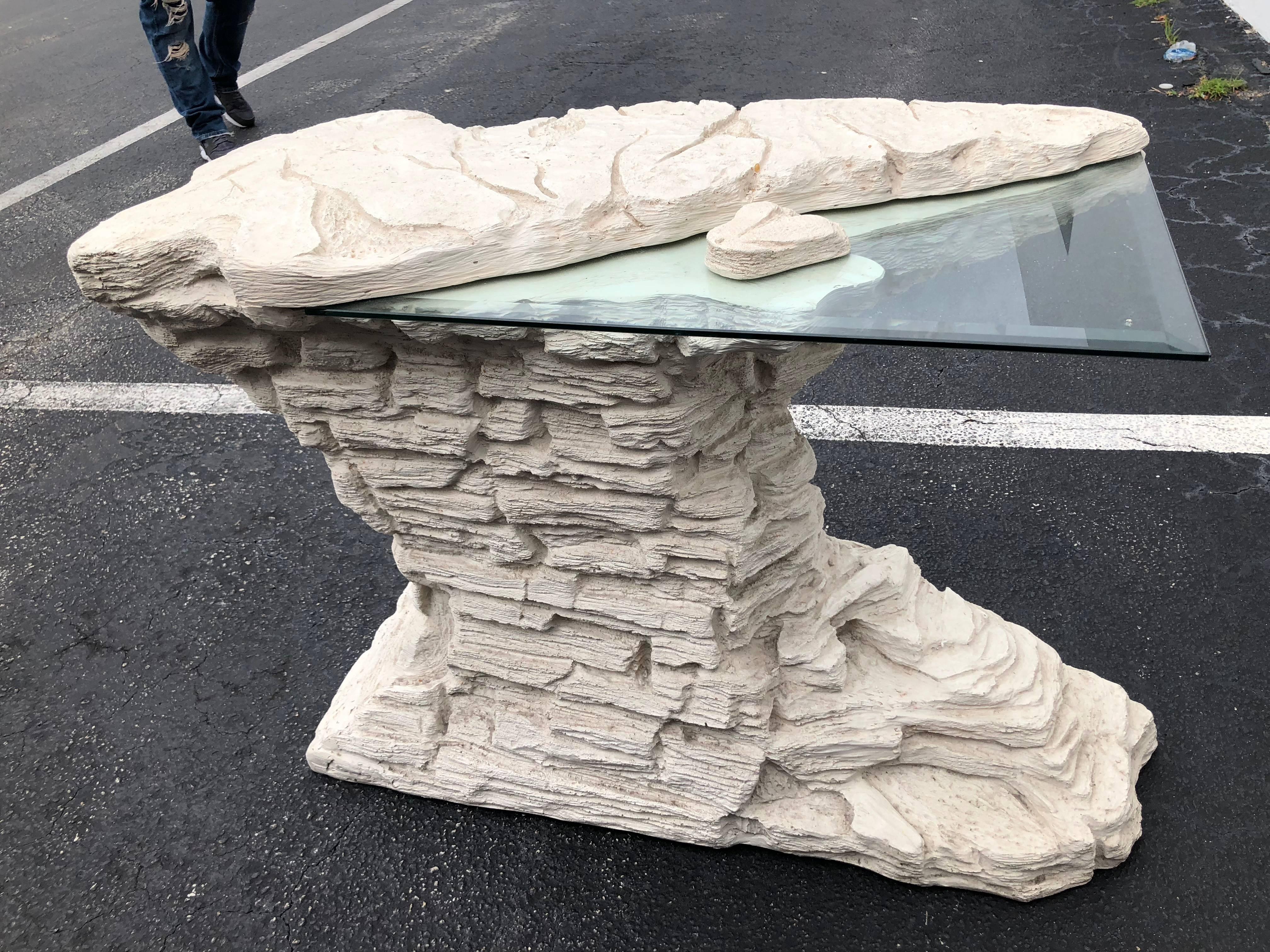 Vintage faux rock stone plaster console table with glass top. In the style of Sirmos.