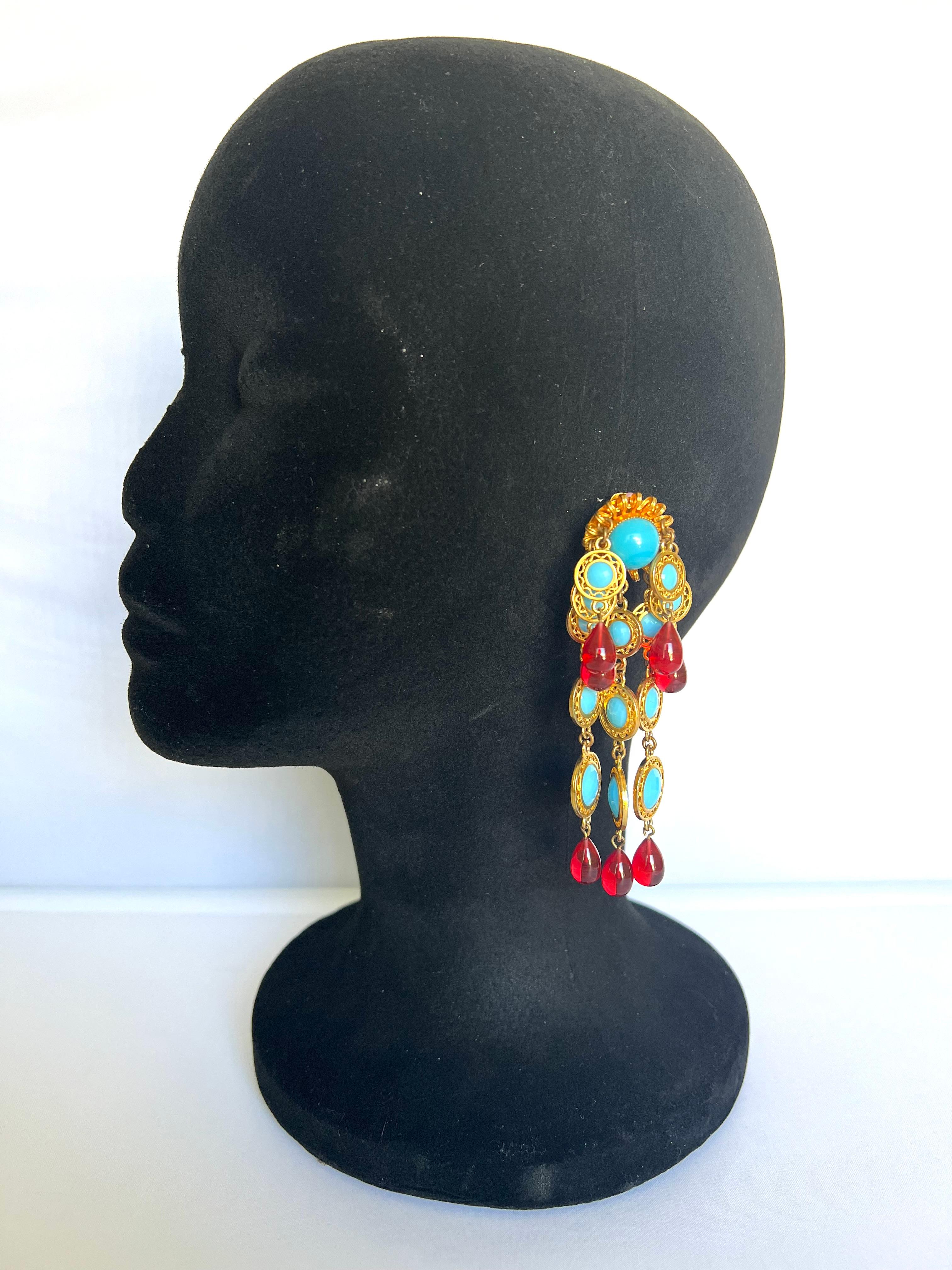 Vintage gilt metal clip-on statement earrings by William de Lillo, LTD circa 1970's. The chandelier earrings feature metal strands adorned with red and turquoise glass-colored cabochons. The earrings come with their original card. Made in New York.