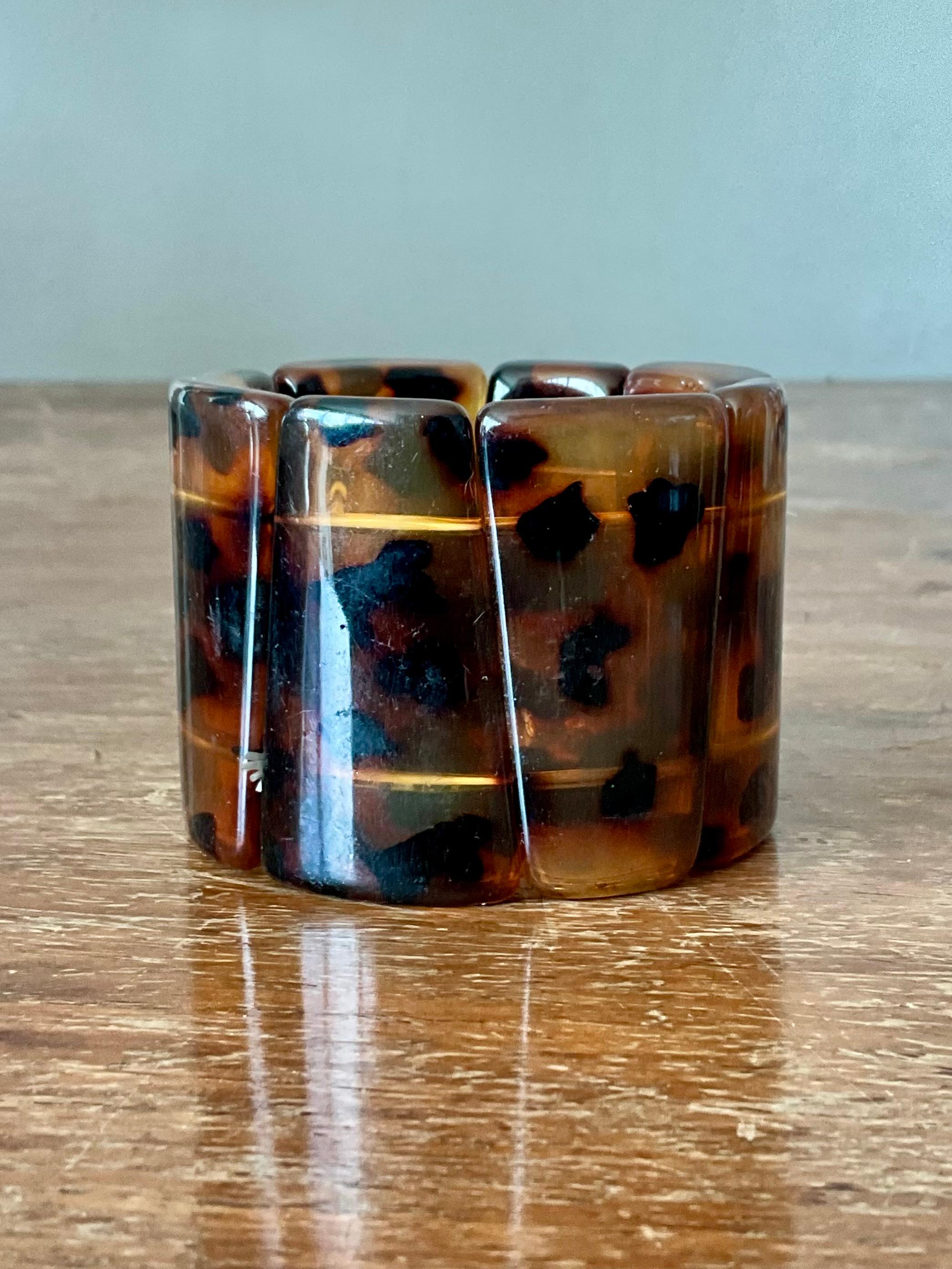 Questo braccialetto vintage in finta tartaruga di bachelite è un accessorio senza tempo che emana una raffinatezza retrò. Realizzato in una plastica che ricorda la tartaruga, il bracciale presenta una ricca marmorizzazione color ambra e marrone