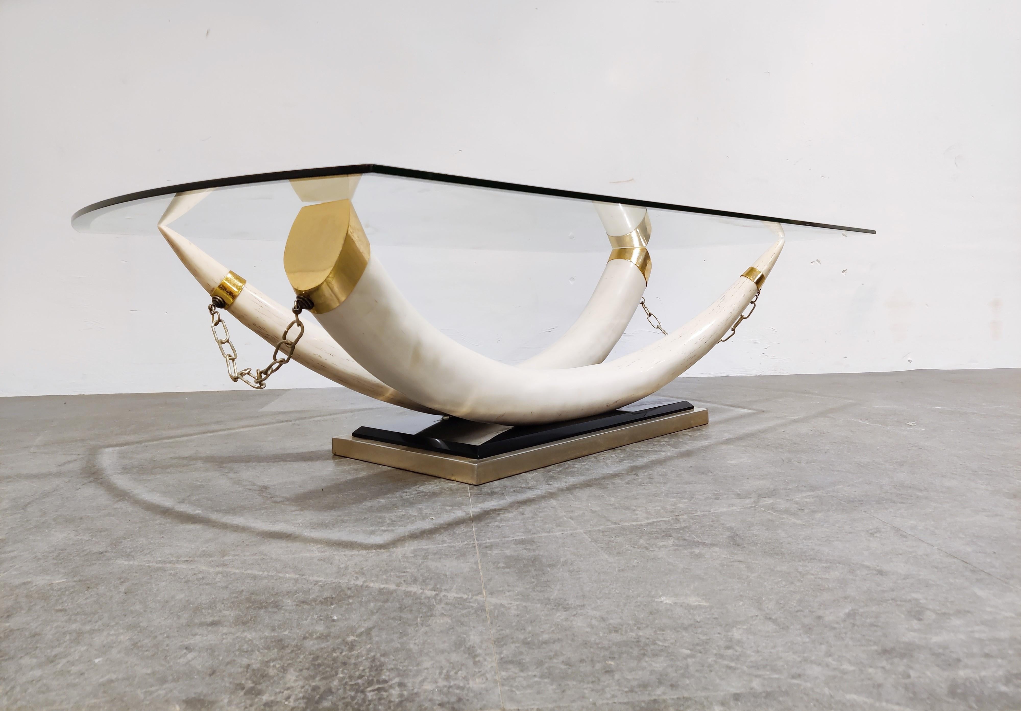 Striking vintage faux tusk coffee table.

The resemblance with real ivory is very close, and the tusks are made of resine with brass ends mounted on a brass and lacquered base.

Original beveled glass top

1980s - Italy

Good