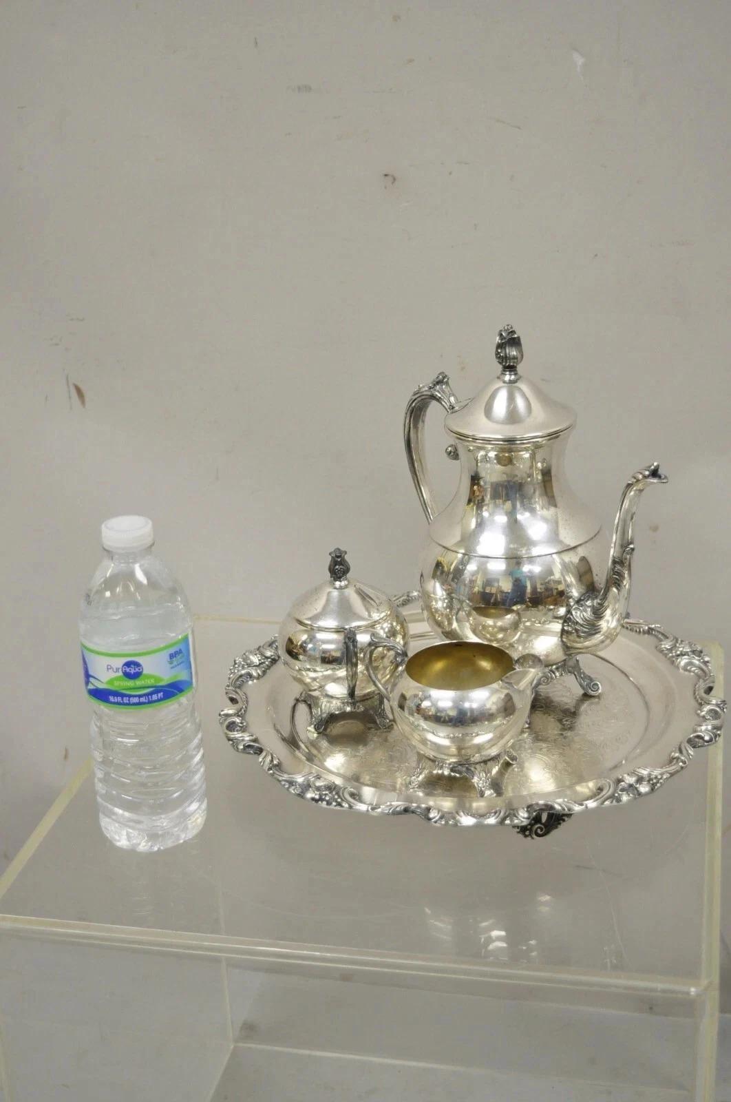 Vintage FB Rogers Silver Plated Tea Set w / Amston Runde Serviertablett - 4 Pc Set. Der Artikel besteht aus einer Teekanne von FB Rogers und einer Zuckerdose mit Deckel, einer runden Servierplatte mit Fuß und verziertem Rand und eingravierter Mitte.
