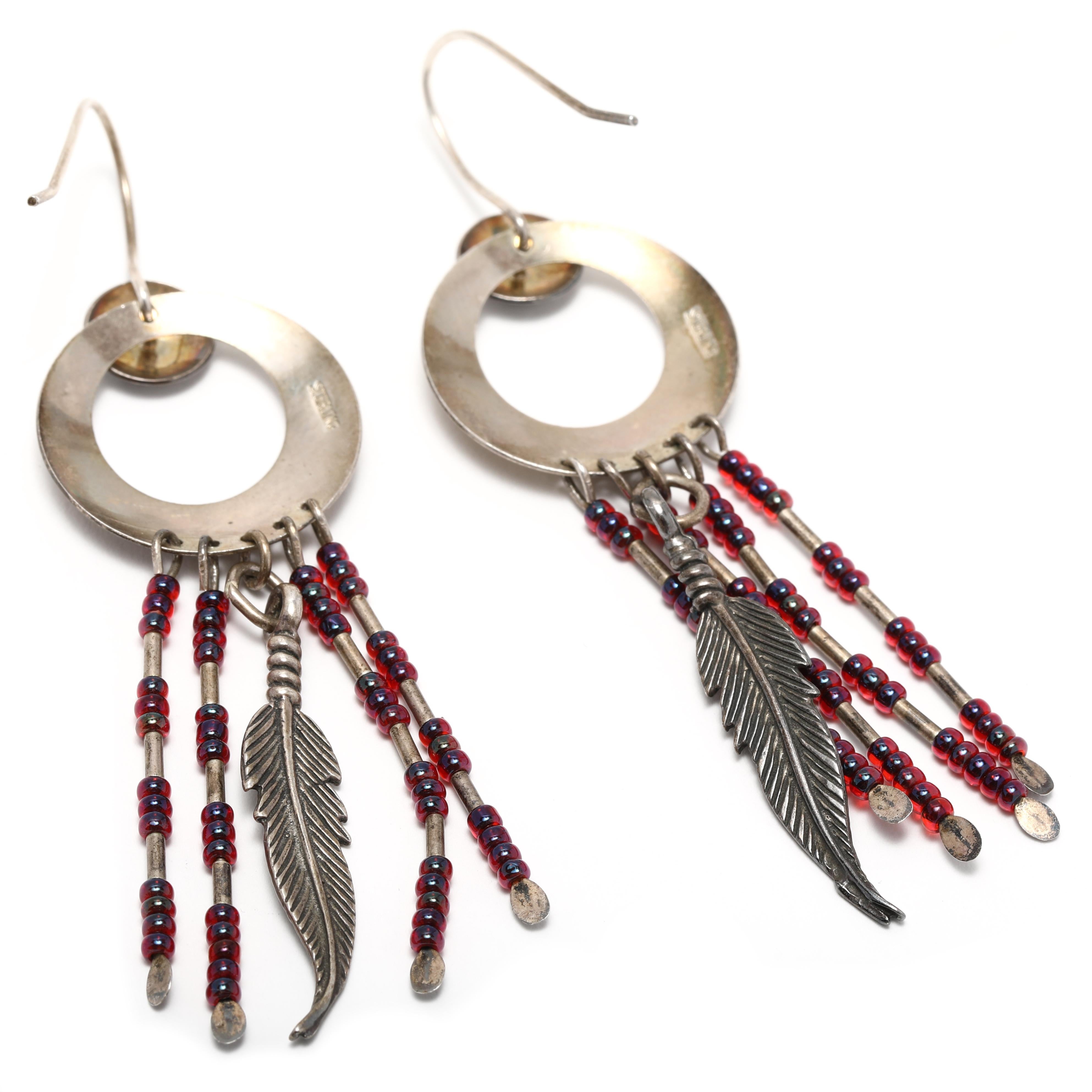 Ces boucles d'oreilles attrape-rêves d'inspiration vintage sont le moyen idéal d'ajouter une touche de style boho à votre look ! Fabriquée en argent sterling, chaque boucle d'oreille est ornée d'un petit charme attrape-rêves, d'une perle rouge et