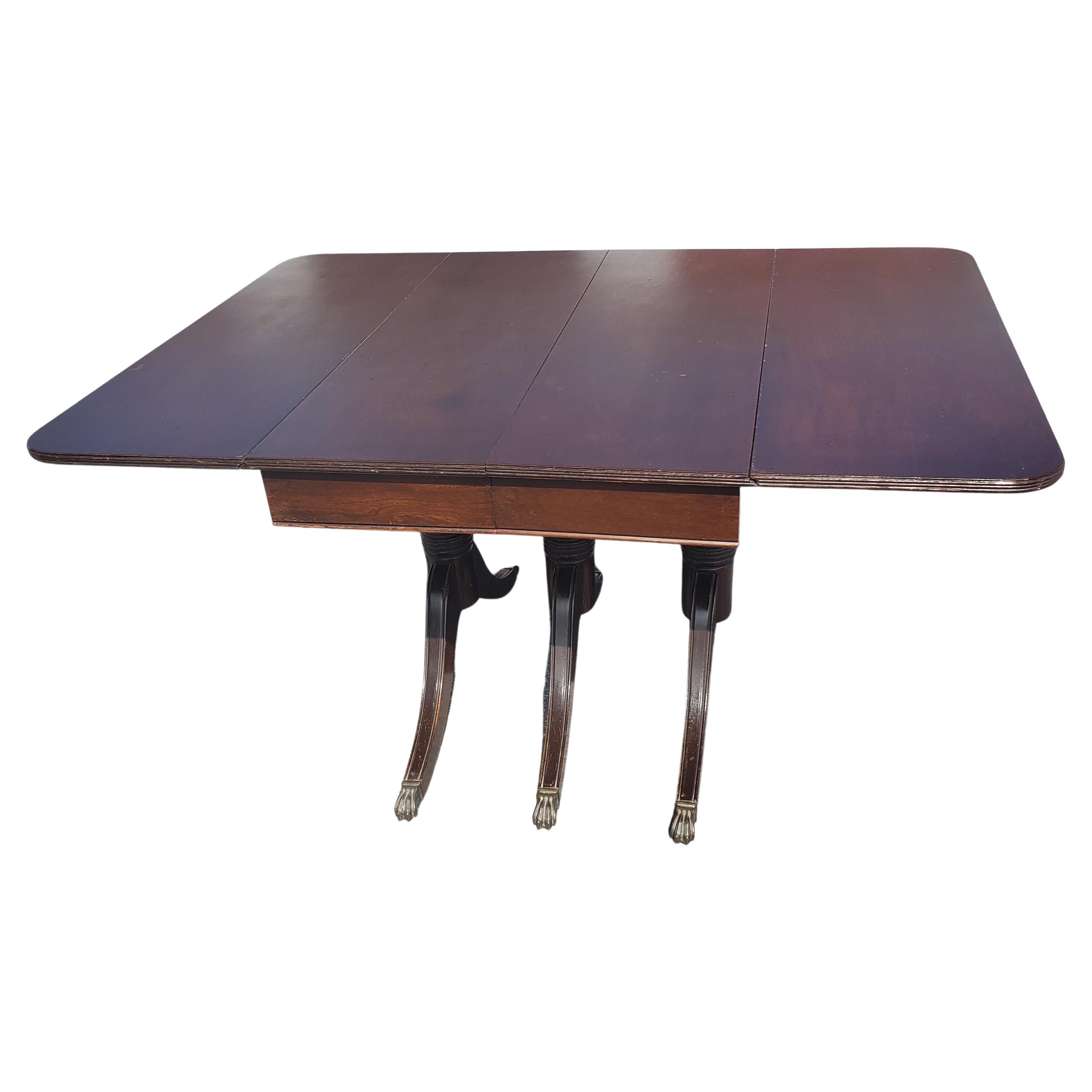 Very practical Vintage Federal Style Triple Pedestal Drop-Leaf Dining Table.
Triple pedestal terminating with antique brass lion paw feet. Original finish with age patina.
Wear appropriate with age and use

WJAB040522.