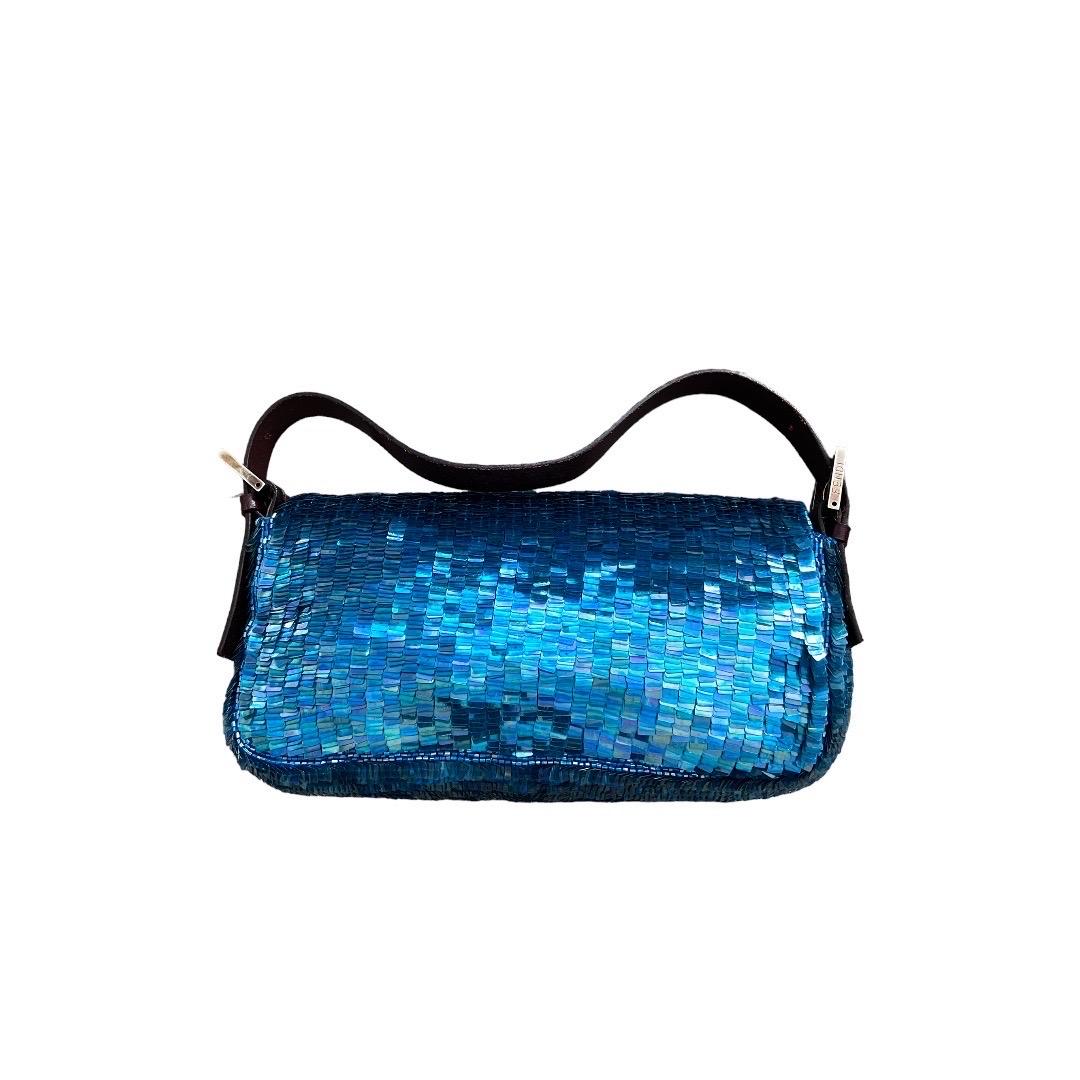 The vintage Fendi Blue Sequin Baguette Bag is a glamorous and iconic piece that epitomizes the brand's timeless elegance. Crafted with meticulous attention to detail, this exquisite bag features shimmering green sequins meticulously hand-embroidered