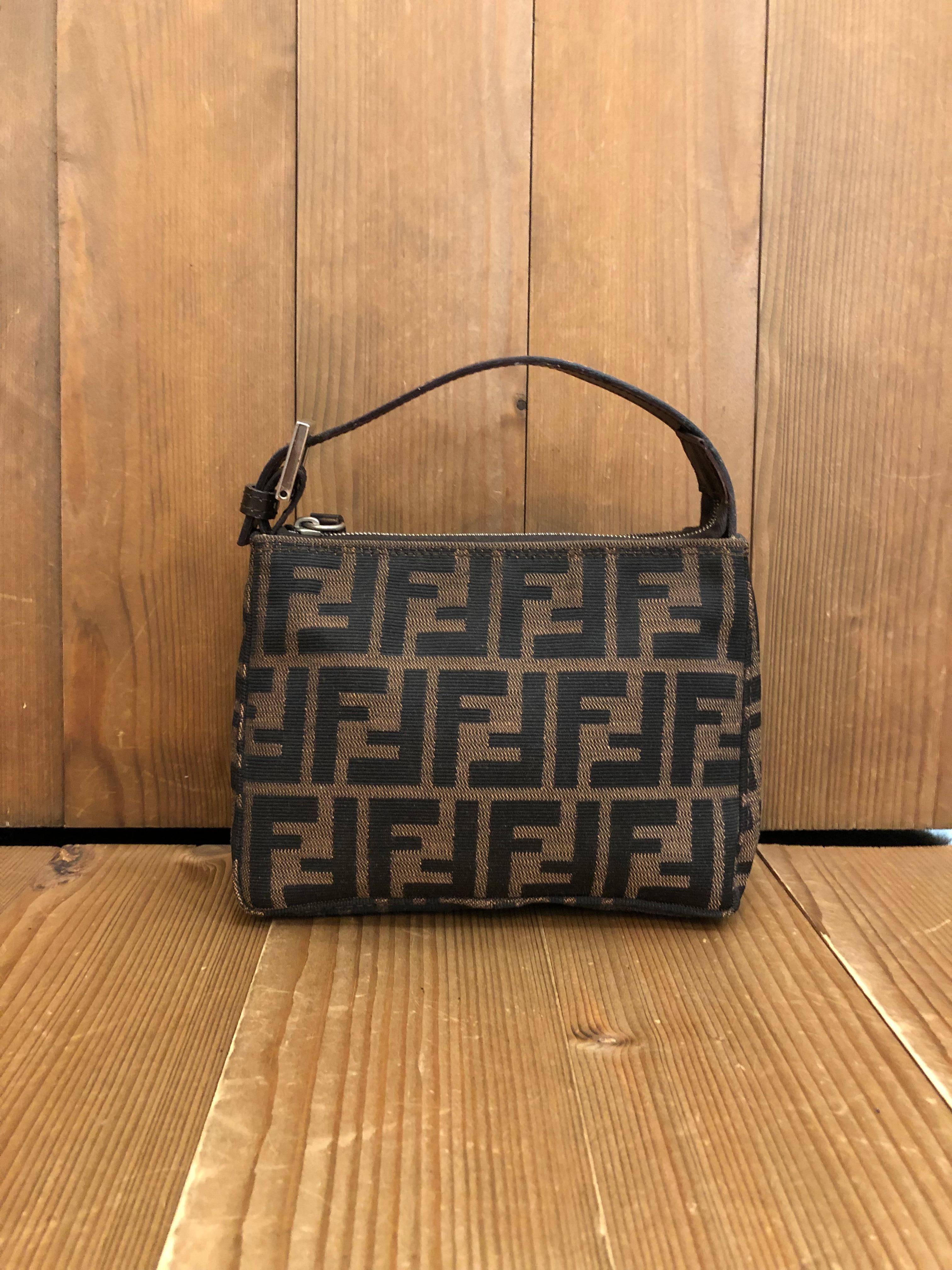 This Vintage FENDI mini pouch handbag is crafted of Fendi's iconi Zucca jacquard in brown/black trimmed with brown leather featuring silver toned hardware. Zipper top closure opens to a new beige interior. Made in Italy. Measures 7 x 5 x 3