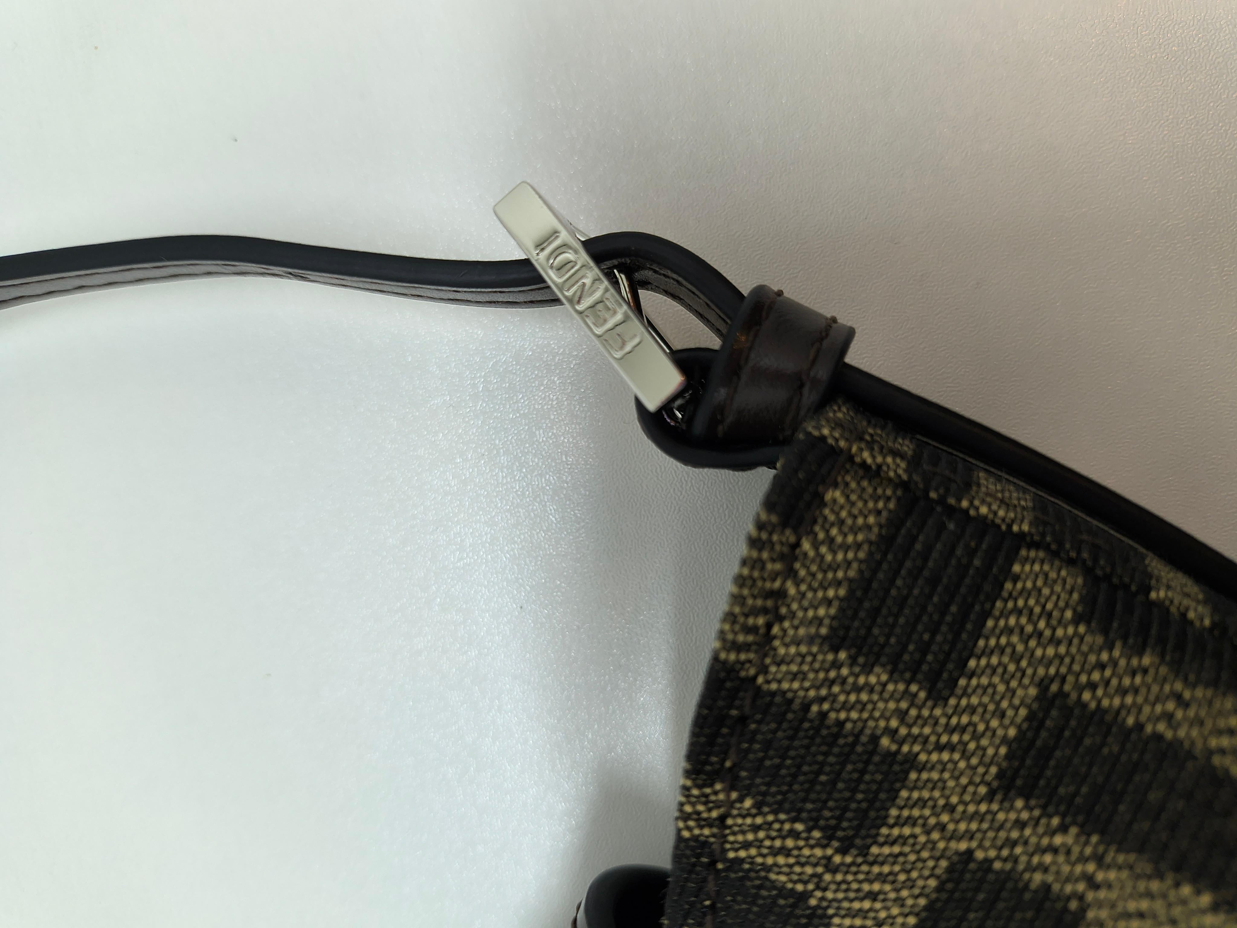 A rare and timeless piece, the Vintage Fendi Greca Mini Half Moon Baguette Clutch Shoulder Bag embodies the elegance and craftsmanship of classic Fendi design. This archival treasure features a sleek half-moon silhouette, adorned with the iconic