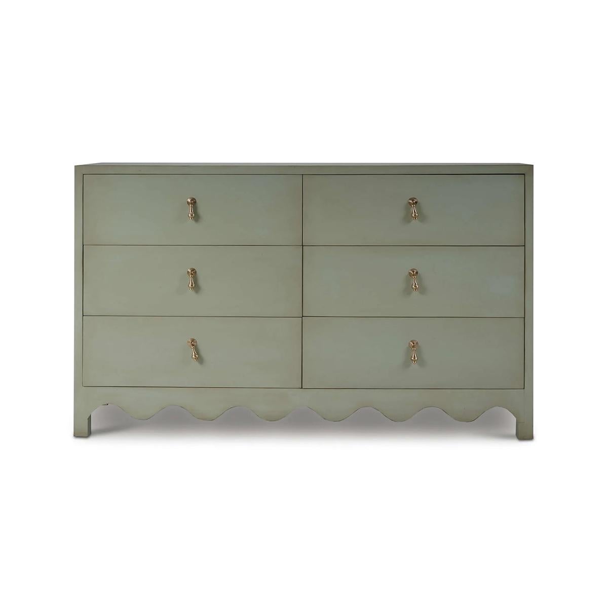 The soft, muted fennel green finish beautifully complements various décor styles, from traditional to contemporary. With scalloped edge detailing along the base and elegant gold-tone drop pull handles, this dresser is more than just a storage