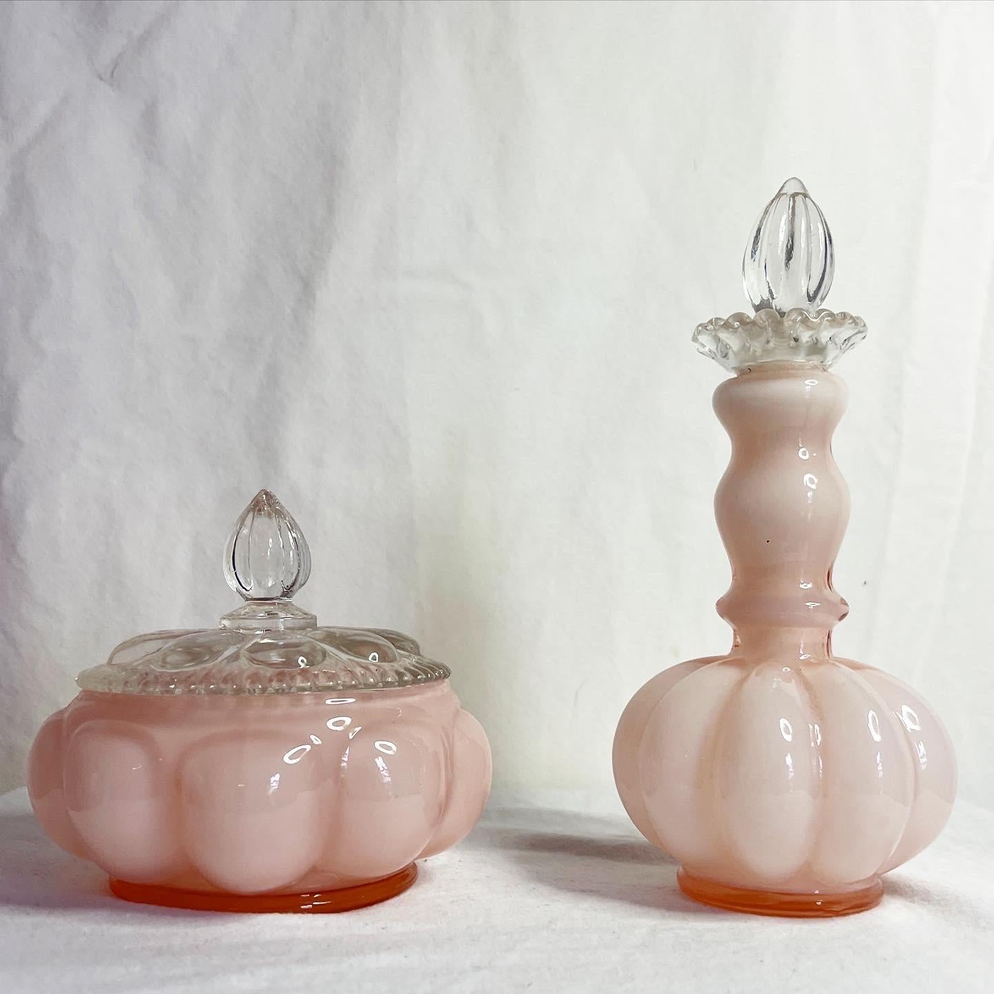 Amazing set of 2 Fenton glass object. Set contains one powder jar and one tall perfume bottle. Displays a Mellon pink glass.

Dish measures: 4.5” W, 4.5” D, 4” H
Bottle measures: 3.25” W, 3.25” D, 7” H.