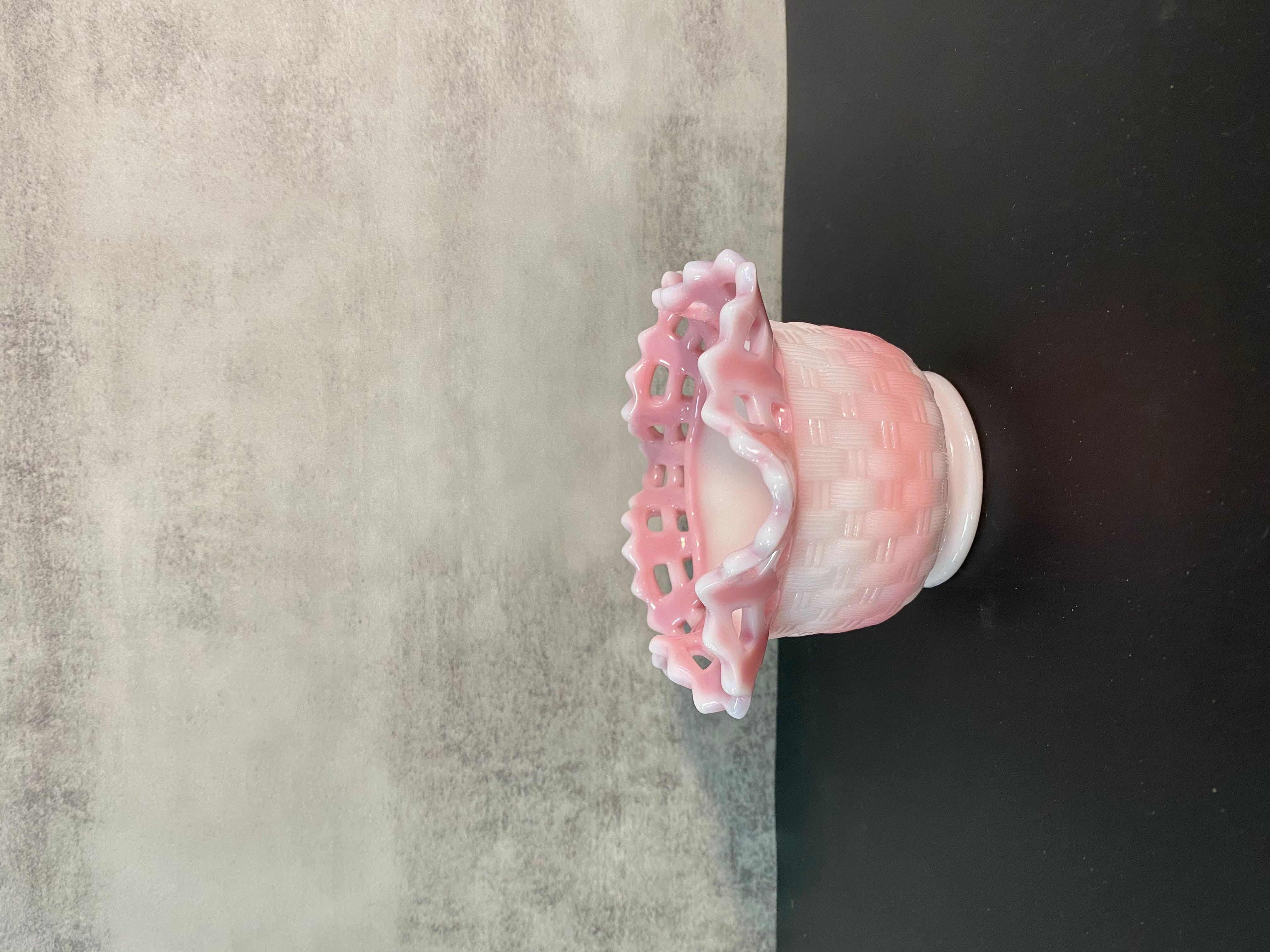 This is a pink and white art glass vase in the Rosalene design from US glass maker Fenton. It has a ruffle edge with cut outs and a basket weave design on the body of the vase.
This vase was purchased from the estate of an avid collector of American