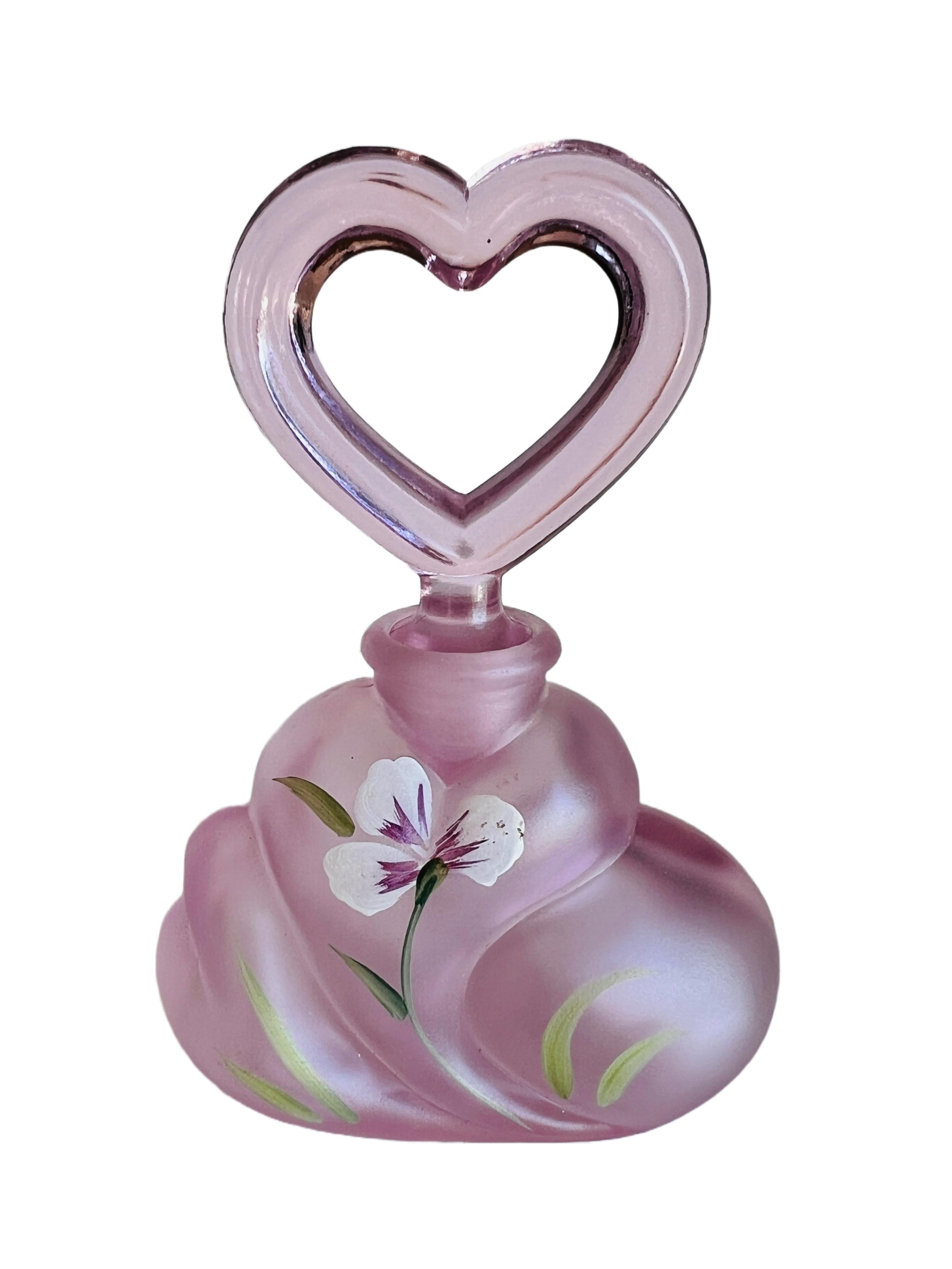 Wunderschöner Parfümflakon aus rosafarbenem Fenton-Glas, verziert mit einem handgemalten Blumendekor und einem charmanten herzförmigen Verschluss. Vom Künstler nummeriert und sowohl von D. Cutshaw als auch von Fenton signiert.

D. Cutshaw ist ein