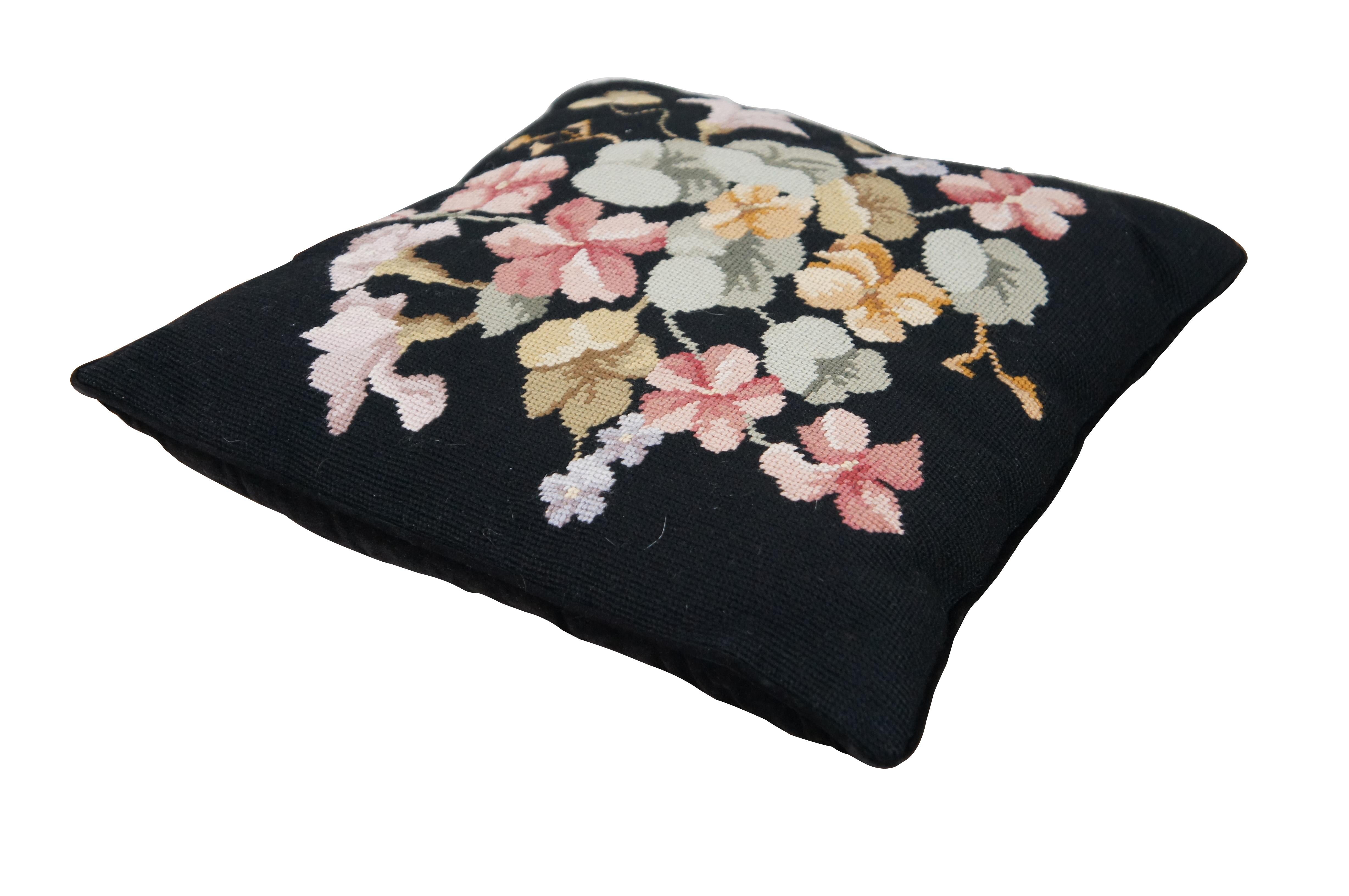 Vintage needlepoint / embroidered throw pillow featuring an array of flowers on a black background, with a black velvet back and fiber filled pillow form / insert. Zipper closure. handstitched but at least one other pillow with matching design /