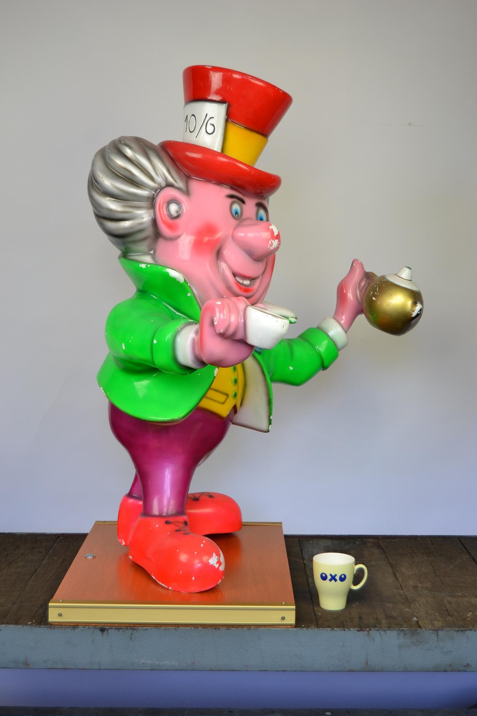 Funny vintage fiberglass coffee man - Mad Hatter - 
Male figurine in sparkling colors with cup and coffeepot, 
based on the Disney's Fairytale Movie 'Alice in Wonderland'.

Placed on a wooden base, this crazy man with large hat, a coffee cup and