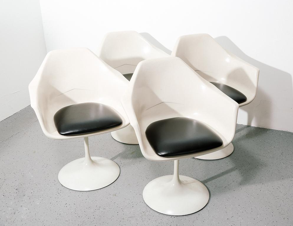 Set of 4 vintage white fiberglass tulip-style dining chairs with black vinyl seat pads. Swivel pedestal bases. In the manner of Eero Saarinen.