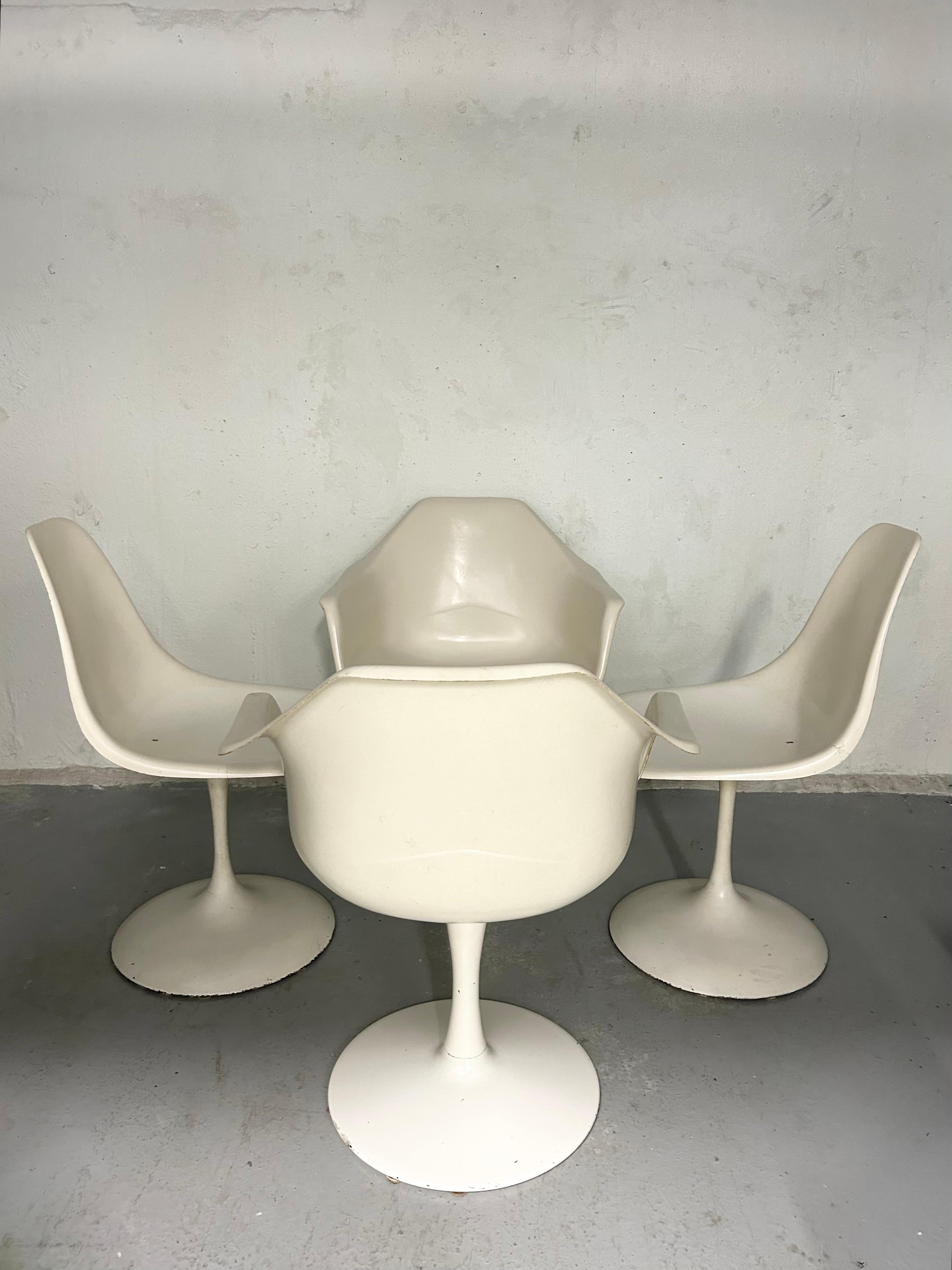Vintage space age fiberglass swivel tulip chairs. In the style of Eero Saarinen. Manufacturer unknown. In good vintage condition. The two chairs without armrests both have a chip on one side edge. One of the chairs with armrests has more wear to the