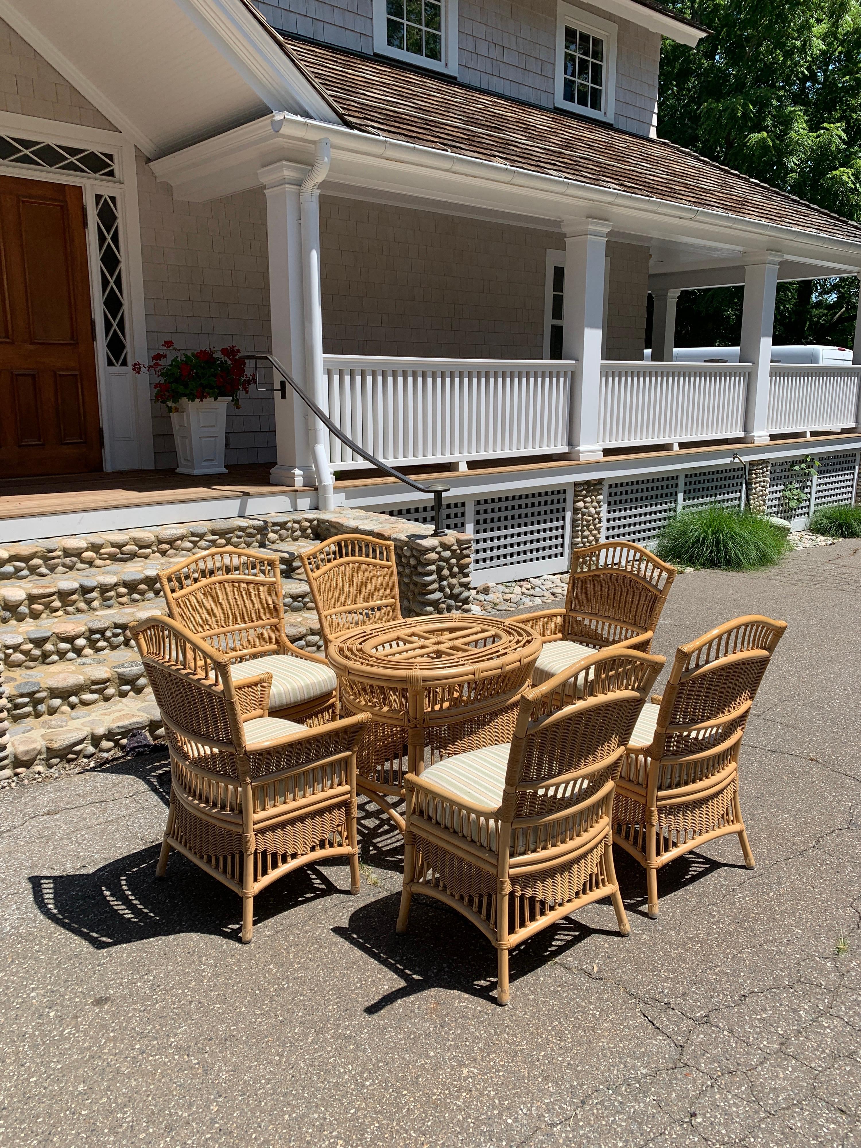 Seven piece vintage Ficks Reed dining set in natural stained reed and rattan. Original cushions included. Two armchairs and four straight chairs. Heavy beveled glass top 66' by 46