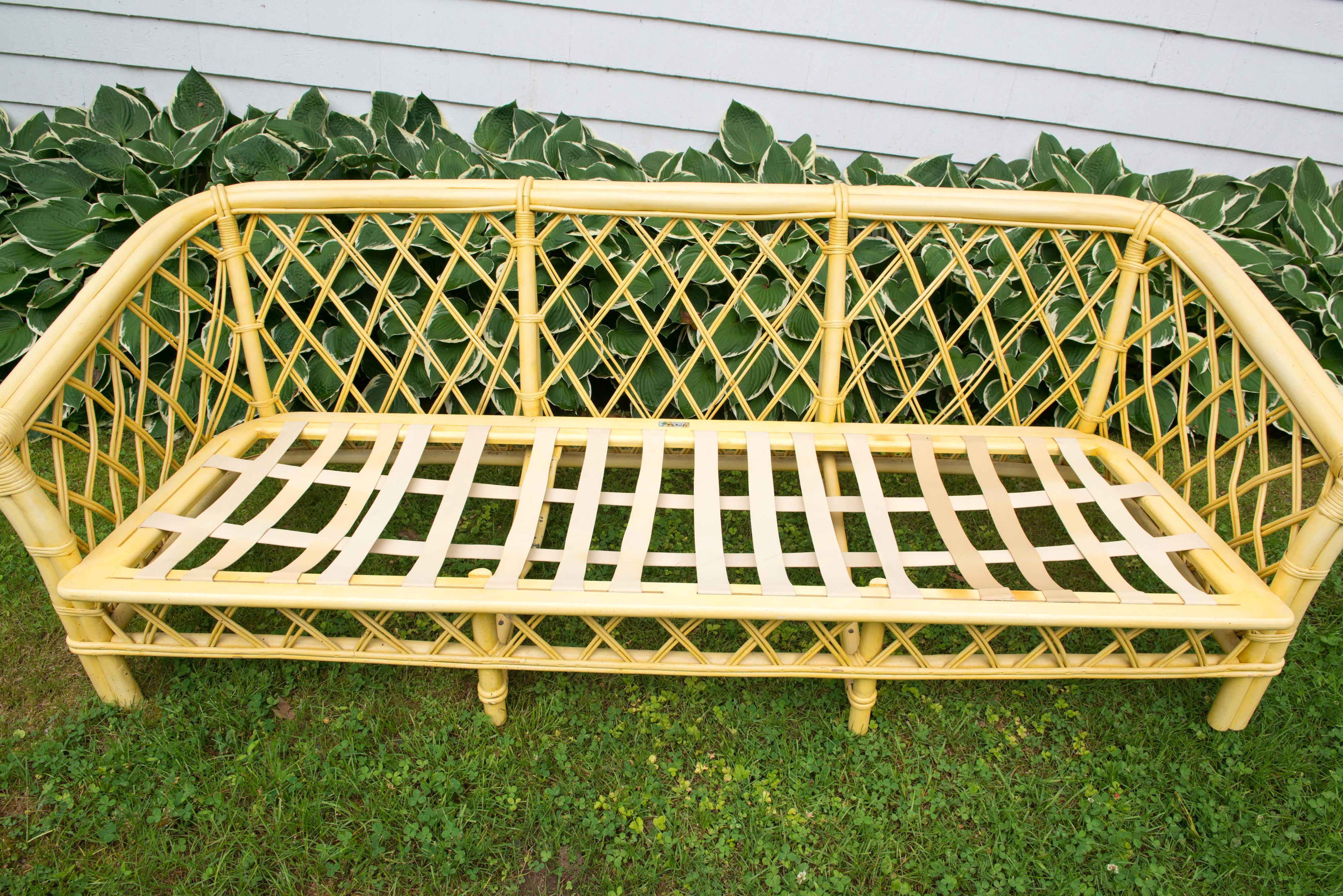 1970s vintage Ficks Reed faux bamboo and rattan sofa with a chinoiserie flair. In original yellow finish with original fabric. Cushions have hardened with age. In remarkable condition. Arm height is 21