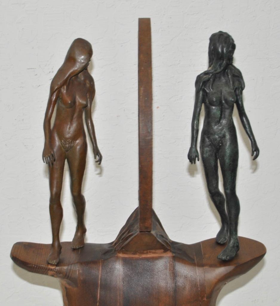 This is a vintage figural nude bronze, wrought iron and wood sculpture, circa 1960s-1970s. 

Patinated bronze women with a wrought iron hoop between them. 

Sits atop a hand crafted wooden base.

The base measures 15