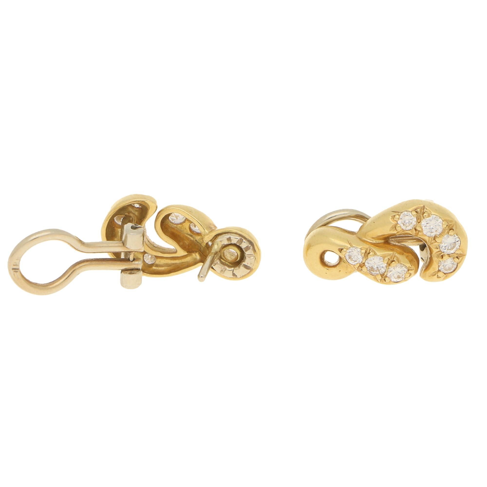 A lovely pair of vintage diamond figure of eight earrings set in 18k yellow and white gold. 
Each earring is designed as a stylised figure of eight motif in yellow gold and is grain-set throughout with seven round brilliant-cut diamonds. The motif