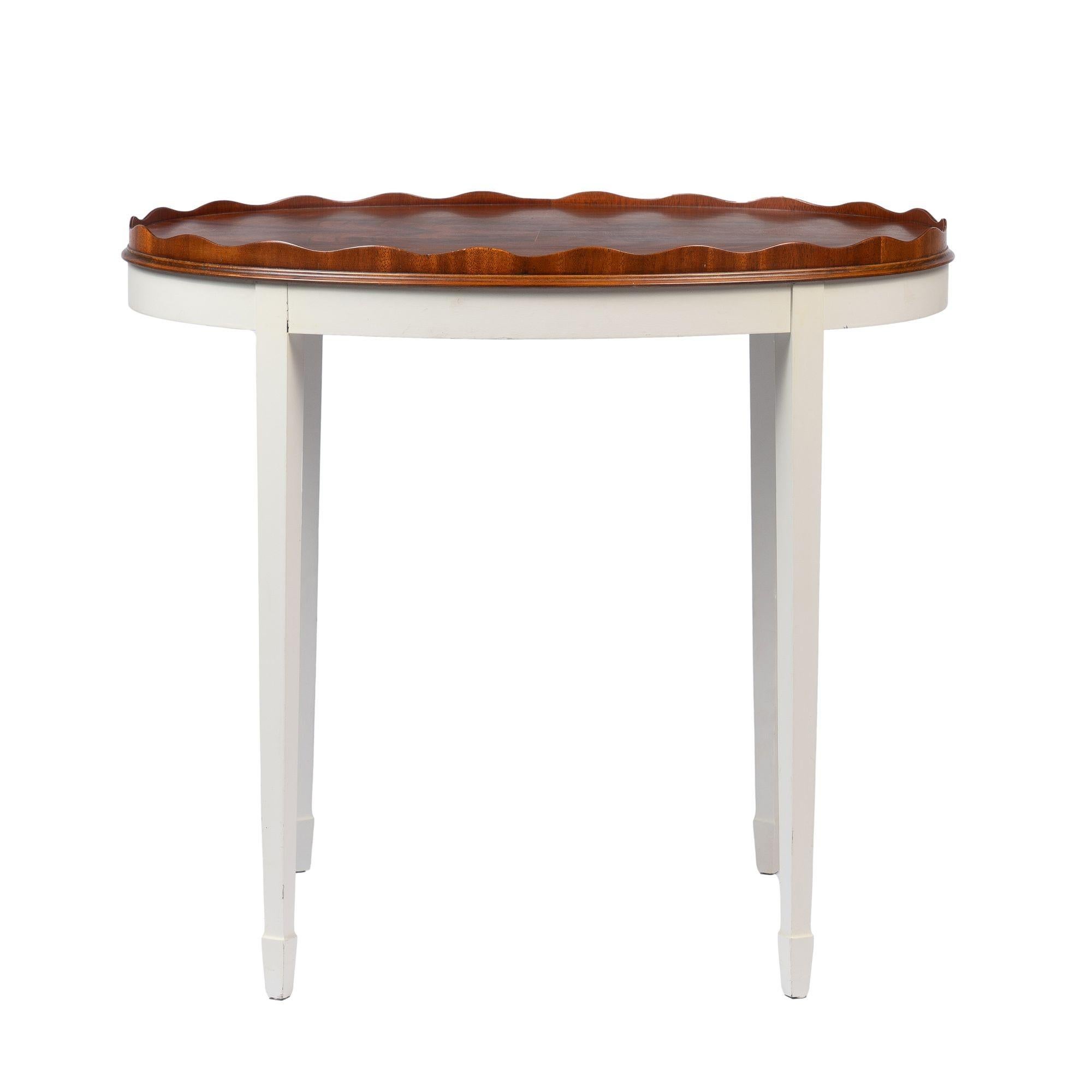 Vintage figured mahogany oval tray with standing scolloped rim mounted on a painted conforming apron with four square tapered legs terminating in spade feet.