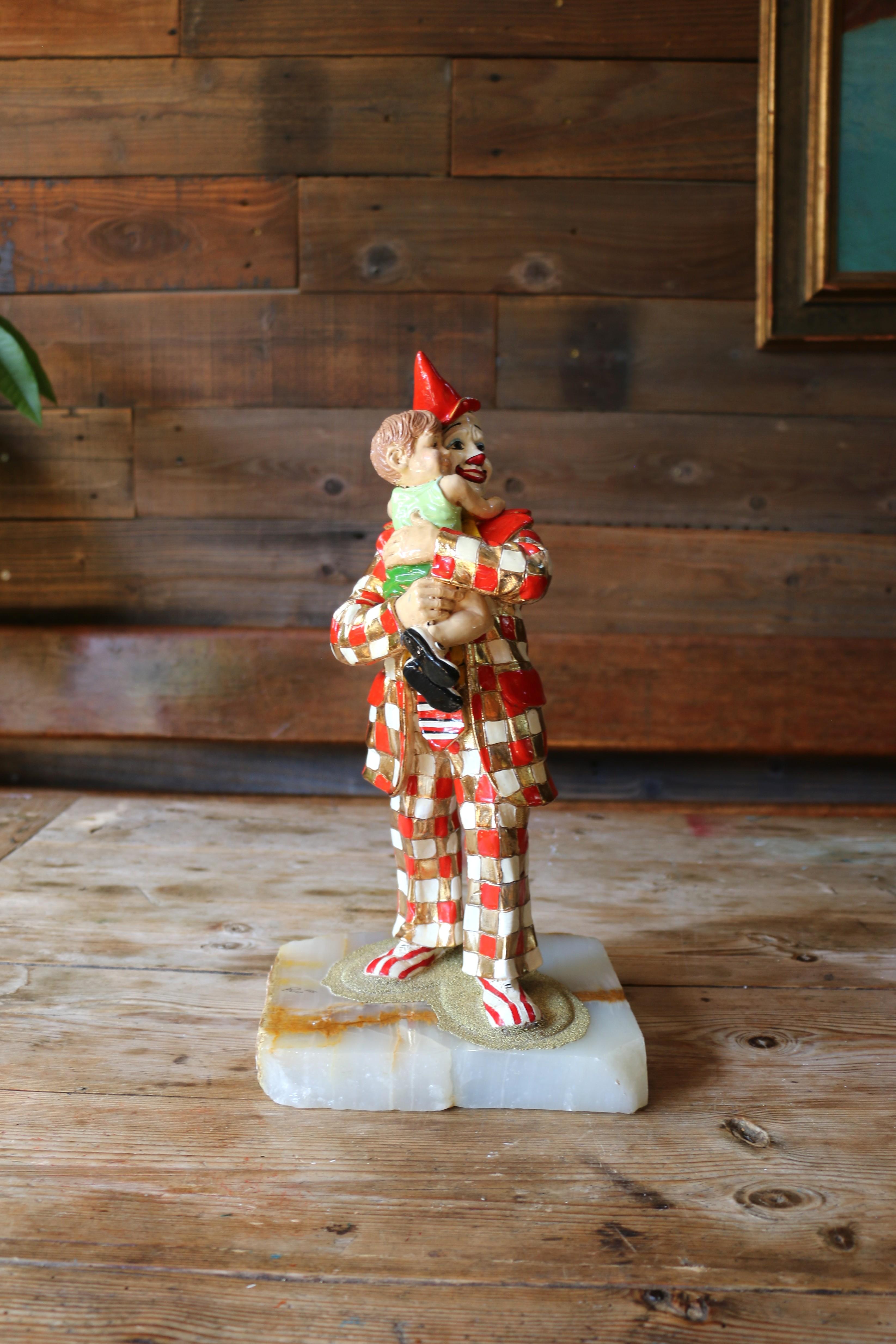 Wonderful Ron Lee clown figurine. It is signed by makers and it is dated 1985. This beautiful piece is depicting a Child Embracing a Clown. This figurine is crafted from white metal, and adorned with 24K gold plating, mounted on onyx bases. It is in