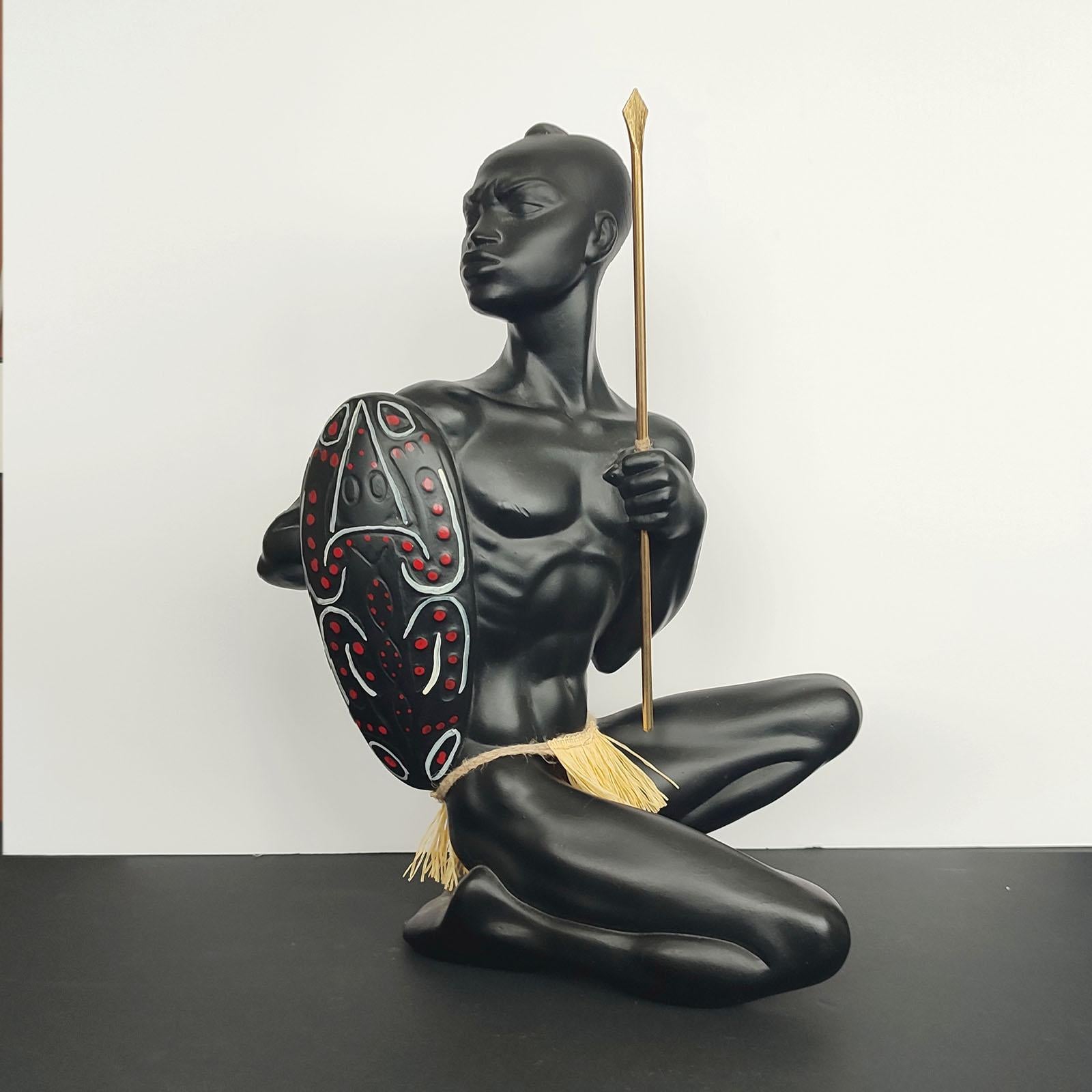 A very beautiful sculpture, displaying an African Warrior with shield and brass spear. Executed in the 1950s, reminding the design of Leopold Anzengruber. Made of black-finished plaster. Very good condition. 
40 cm [15 3/4 in] high.
