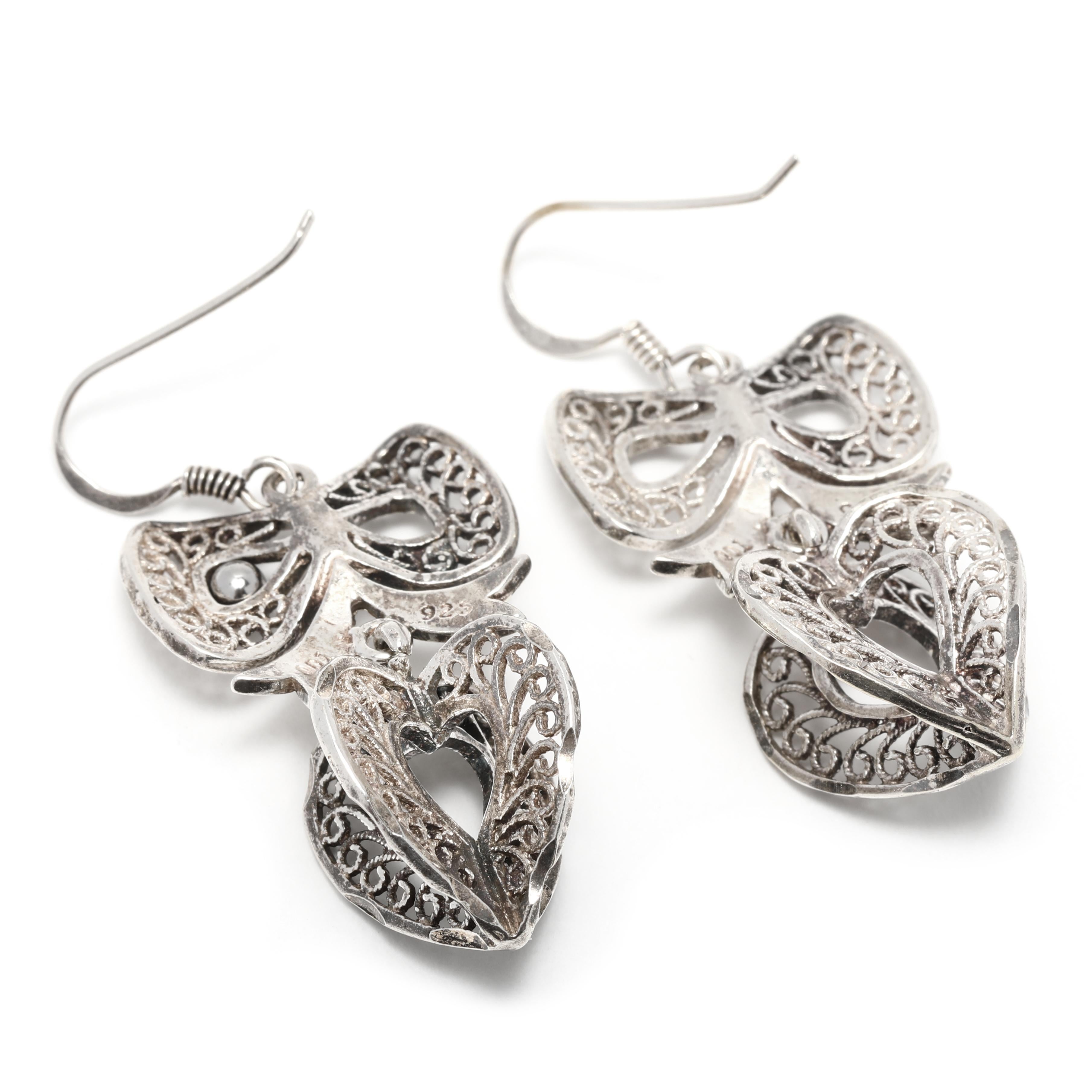 These beautiful vintage sterling silver filigree bow heart dangle earrings are sure to be a stunning addition to any jewelry collection. With a total length of 1 3/4 inches, these large bow dangle earrings have intricate filigree detailing and a