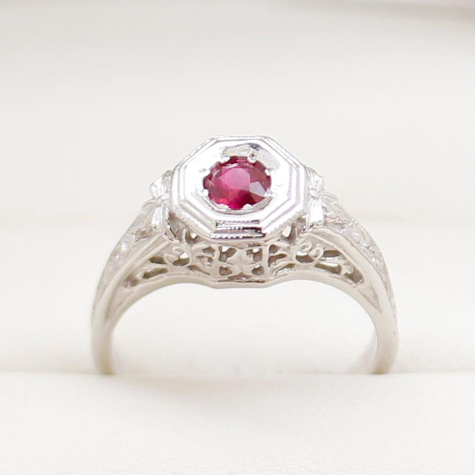 14ct White Gold Ring, narrow, low half round, tapered shank with open back, polished finish, stamped (14K).

The item contains:

One Moustache set round natural ruby, colour is 