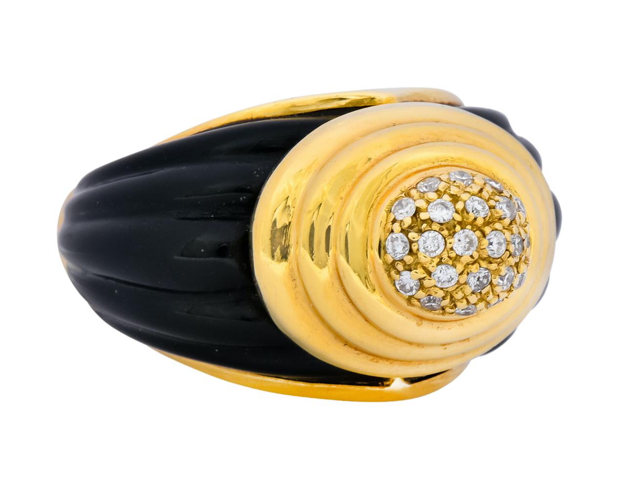 Centering a round oval pavé field set with round brilliant cut diamonds weighing approximately 0.18 carat, eye-clean and white

With a graduating ridged gold surround

Flanked by carved fluted black onyx shoulders

Inner shank features black