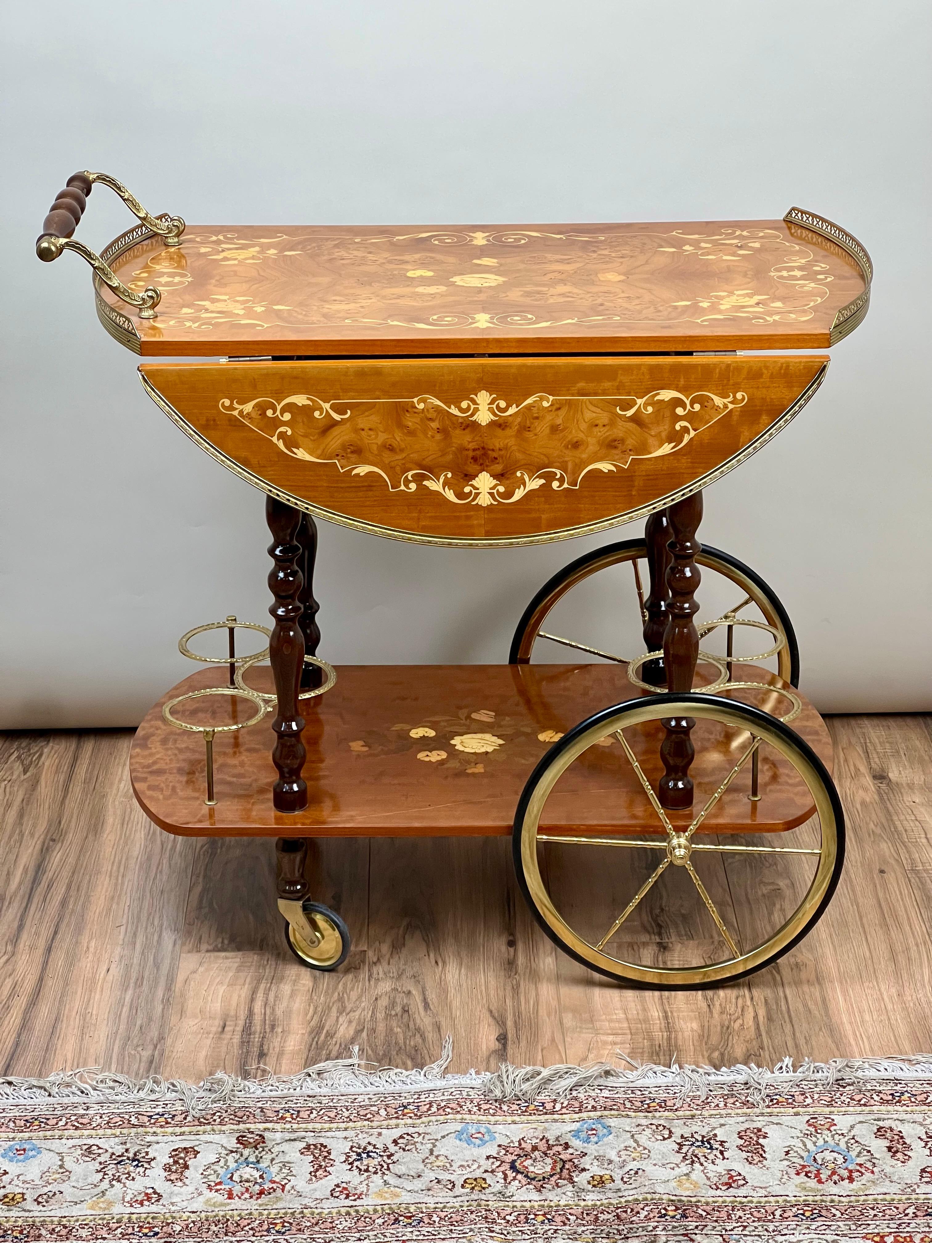 Questo elegante carrello da tè italiano di Sorrento è un capolavoro di intarsio, con squisiti intarsi floreali incastonati in lussuose impiallacciature di radica. Il piano a ribalta si espande per creare un'ampia superficie di servizio, incorniciata