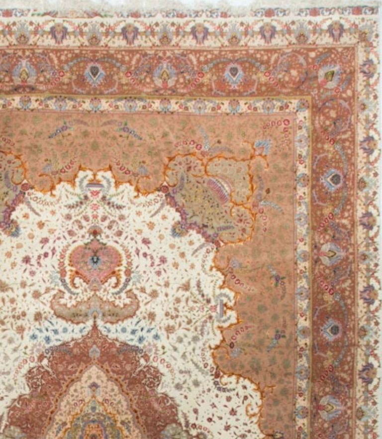 This fine Tabriz rug is typical of this style with the ivory diamond central medallion encircling a smaller floral design all enclosed by the main field. The main border surrounded by two minor borders. Measures: 12'9