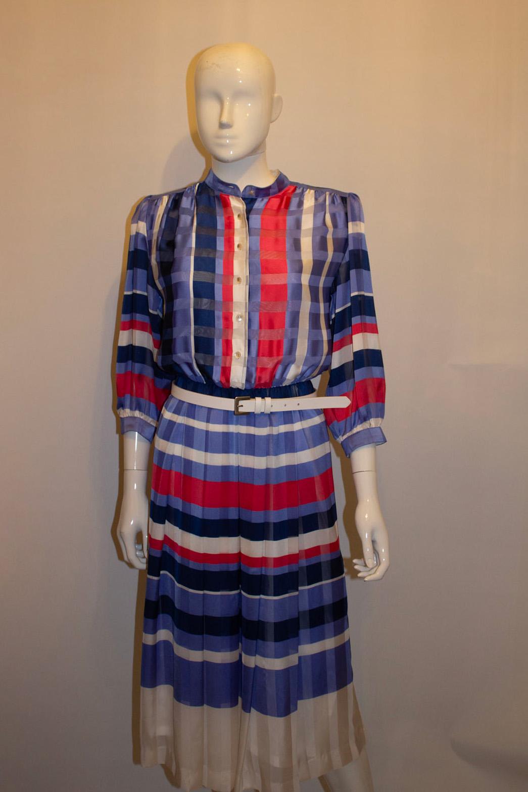 A charming vintage day dress by Fink Model. In a pretty colour combination of rose pink, lilac and white . The dress has a button front opening and button cuffs. It has a a detachable collar, elasticated waist  and a white belt.  Size